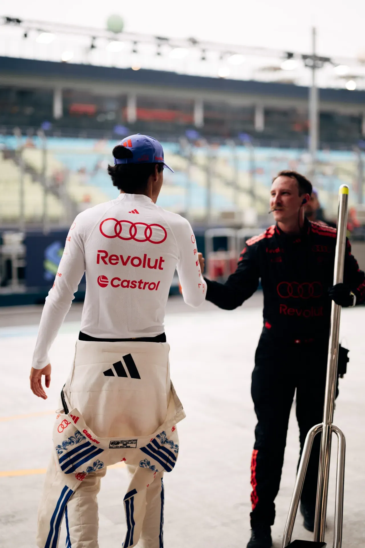 Gabriel Bortoleto of the Audi Revolut F1® Team, seen from behind, shakes hands with a mechanic in the pit lane in Singapore