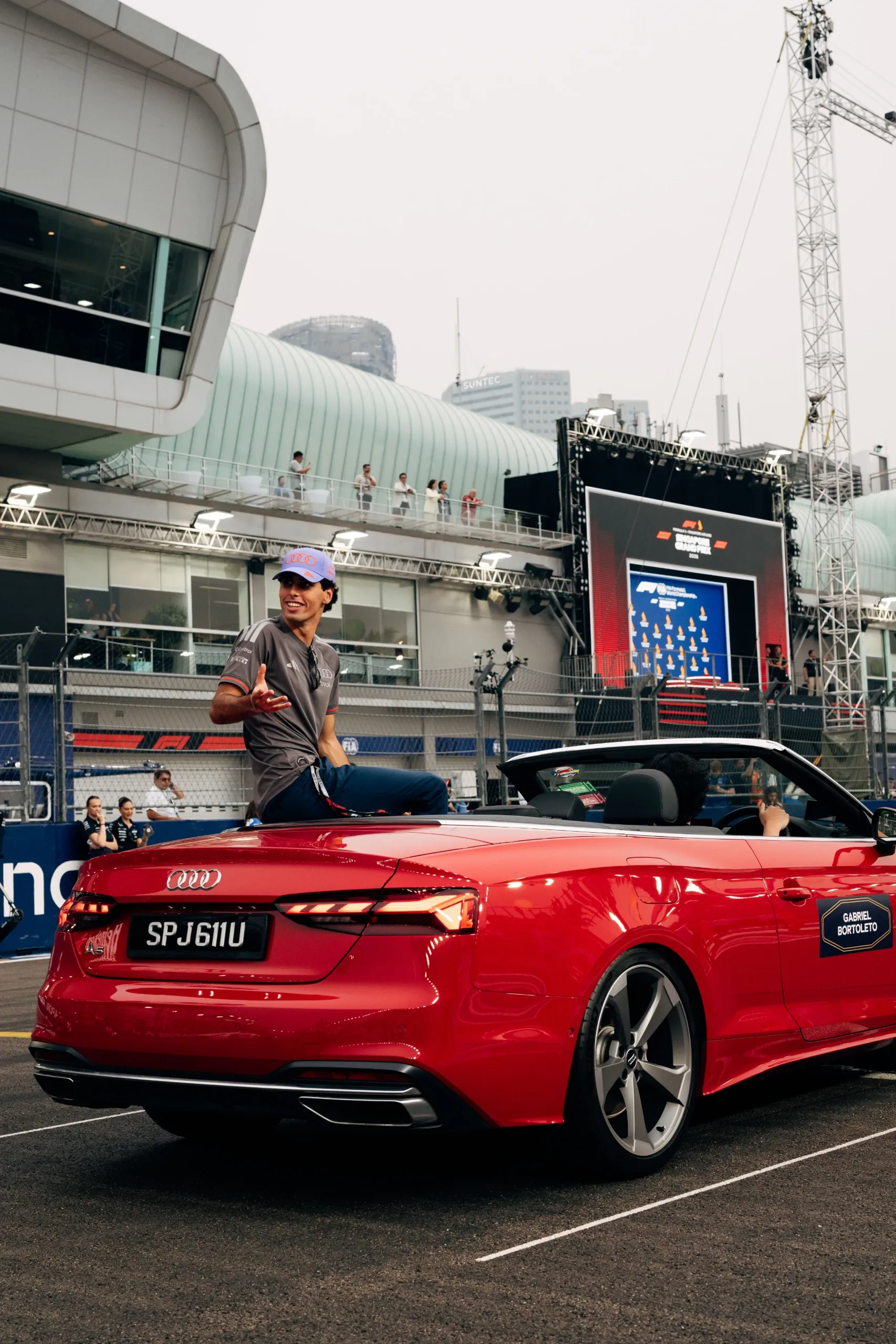 Gabriel Bortoleto of the Audi Revolut F1® Team sitting on the back of a red Audi convertible in Singapore