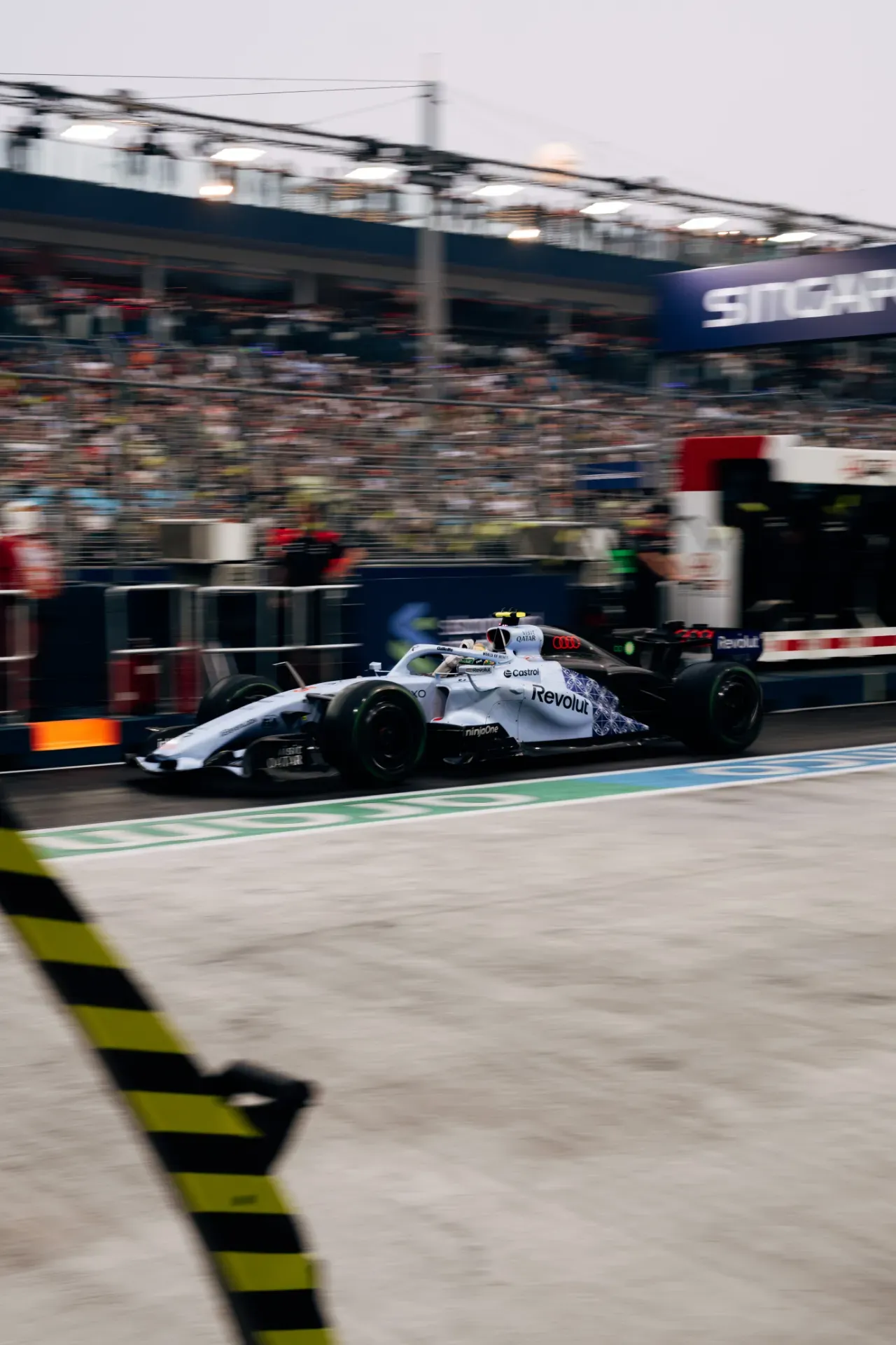 Car of the Audi Revolut F1® Team driving along the pit lane in Singapore, with grandstands behind