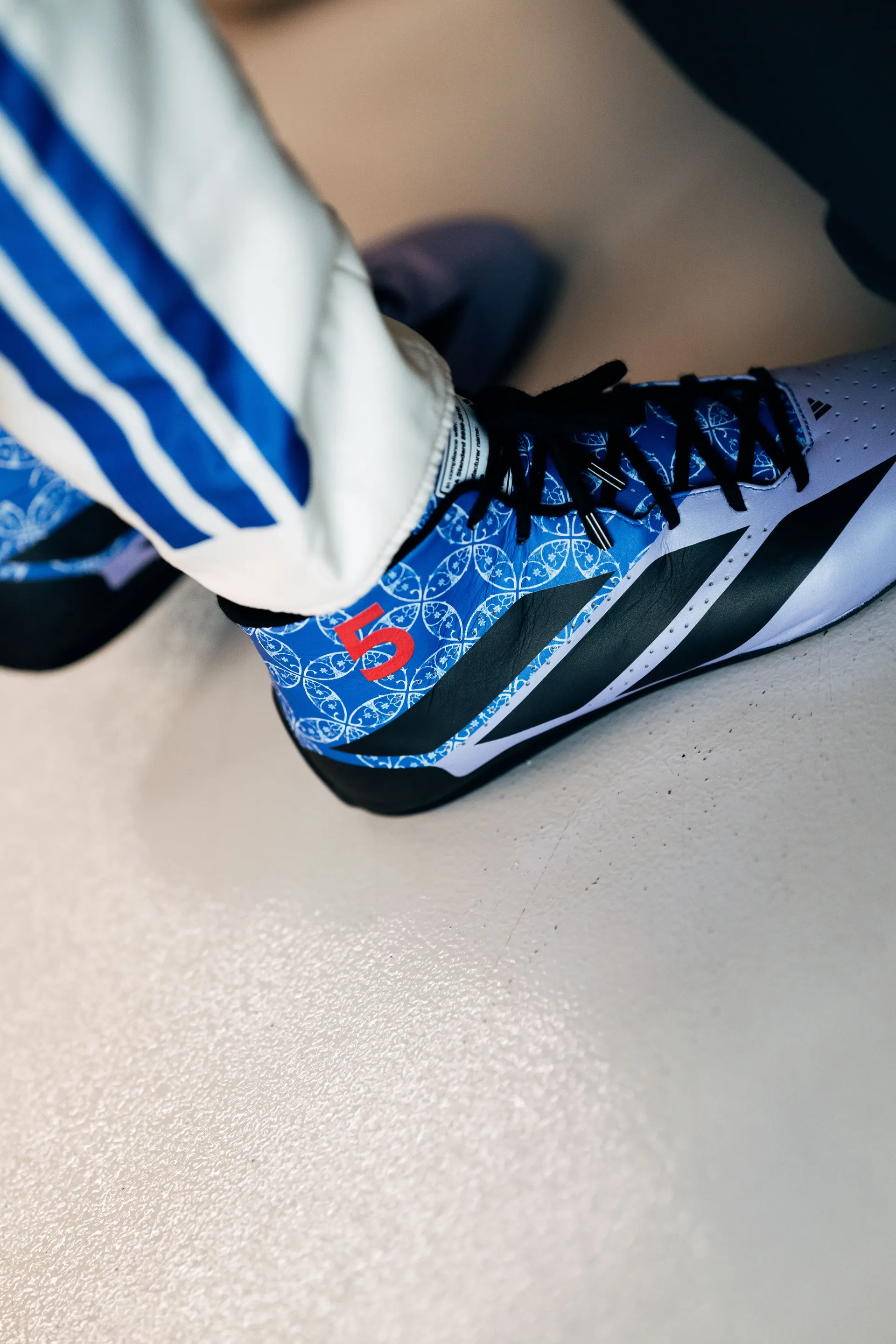 Close-up of Gabriel Bortoleto’s Audi Revolut F1® Team race boot with his number 5 on a blue tile pattern.