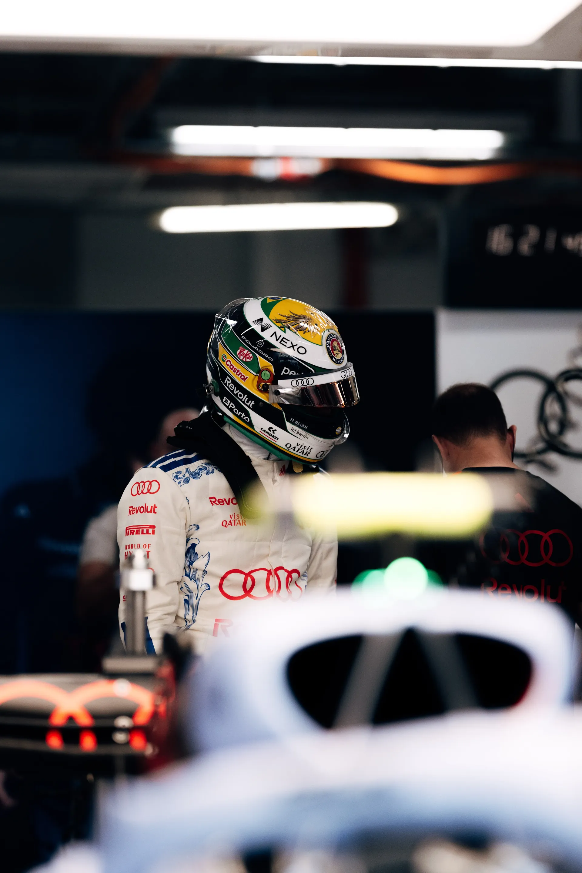 Gabriel Bortoleto of the Audi Revolut F1® Team in his green and yellow helmet in the garage, the car’s halo blurred in the foreground.