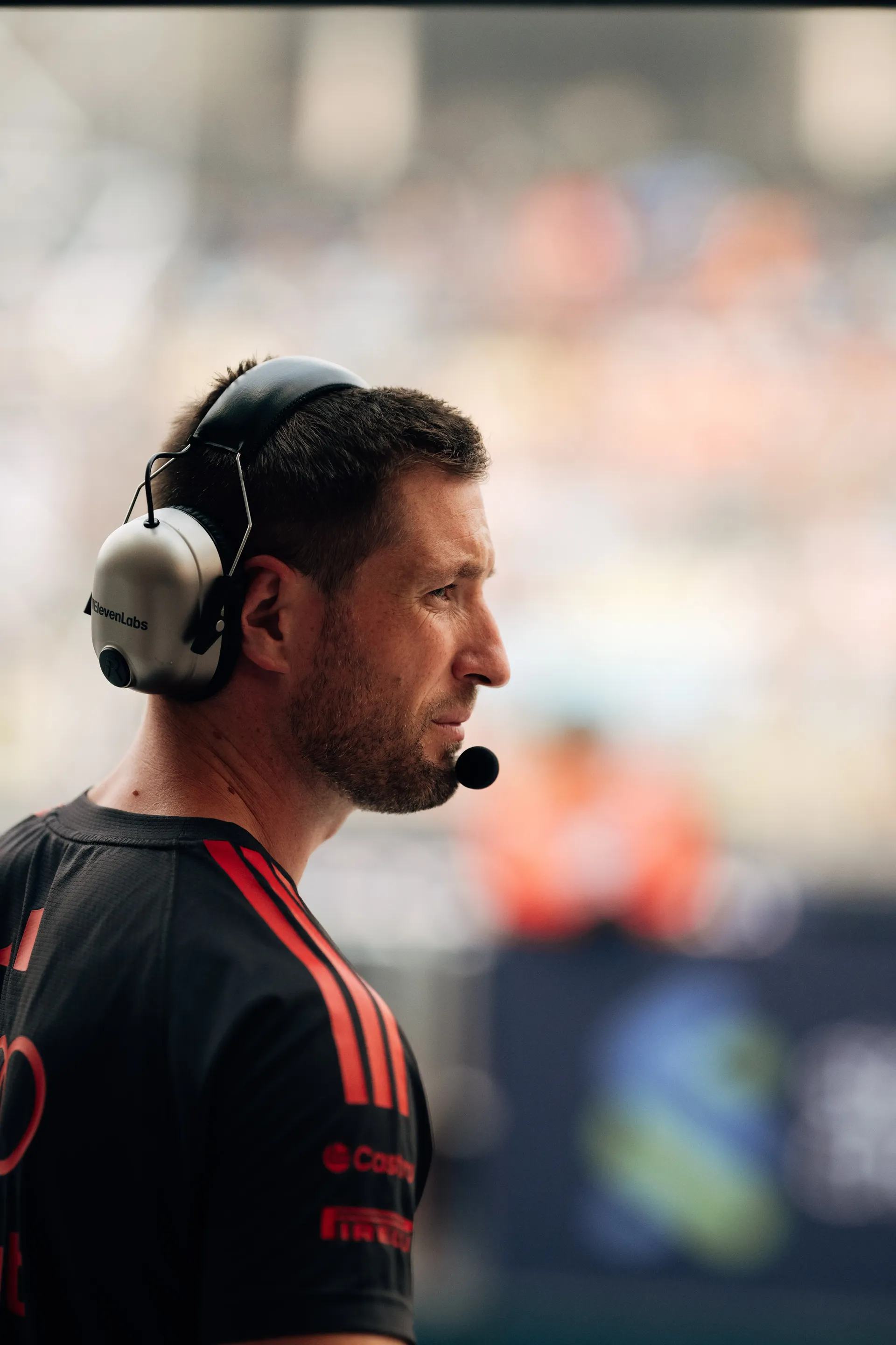Audi Revolut F1® Team mechanic wearing a headset in the pit lane, seen in profile.