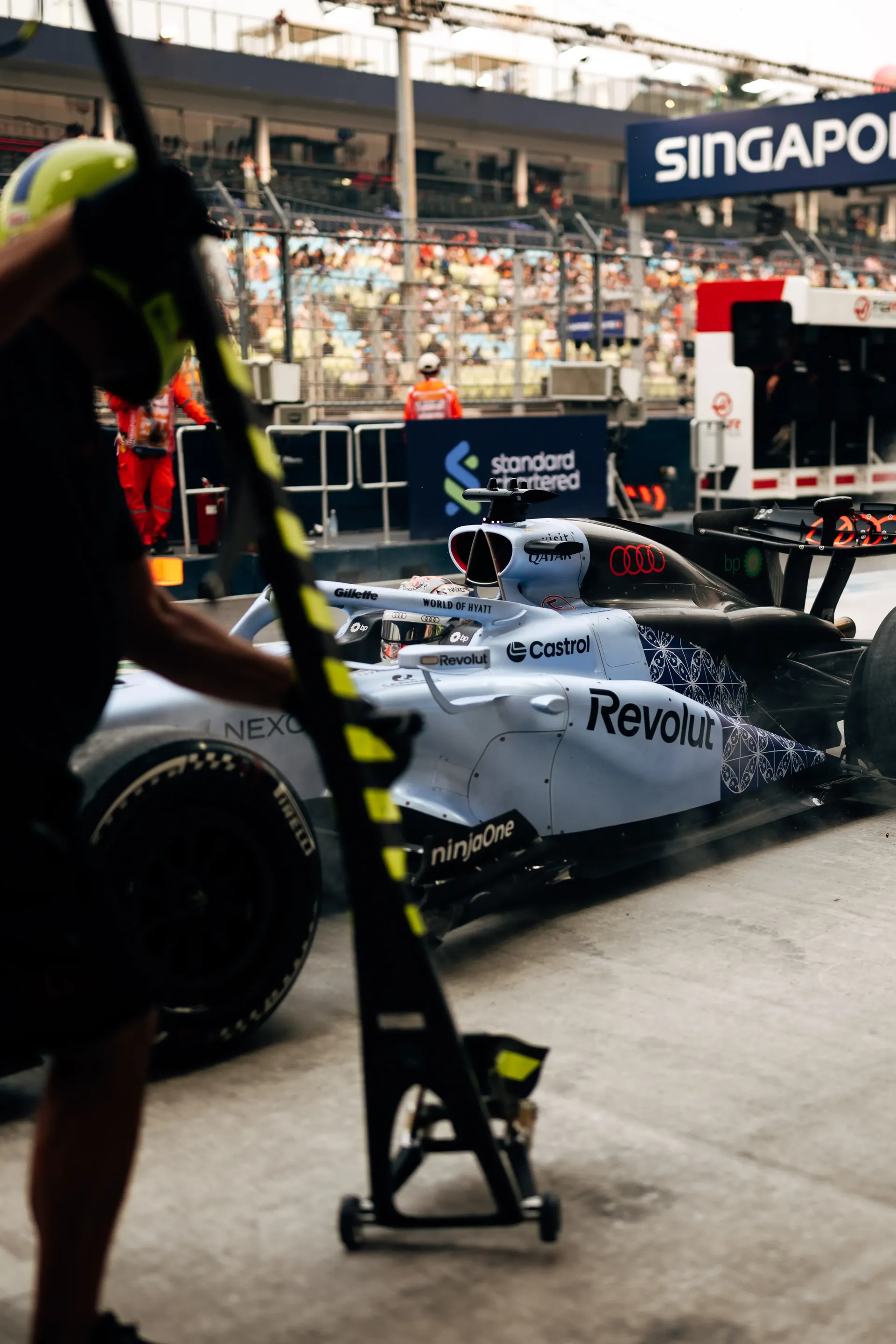 Audi Revolut F1® Team mechanic holding the front jack beside the car in the pit lane.