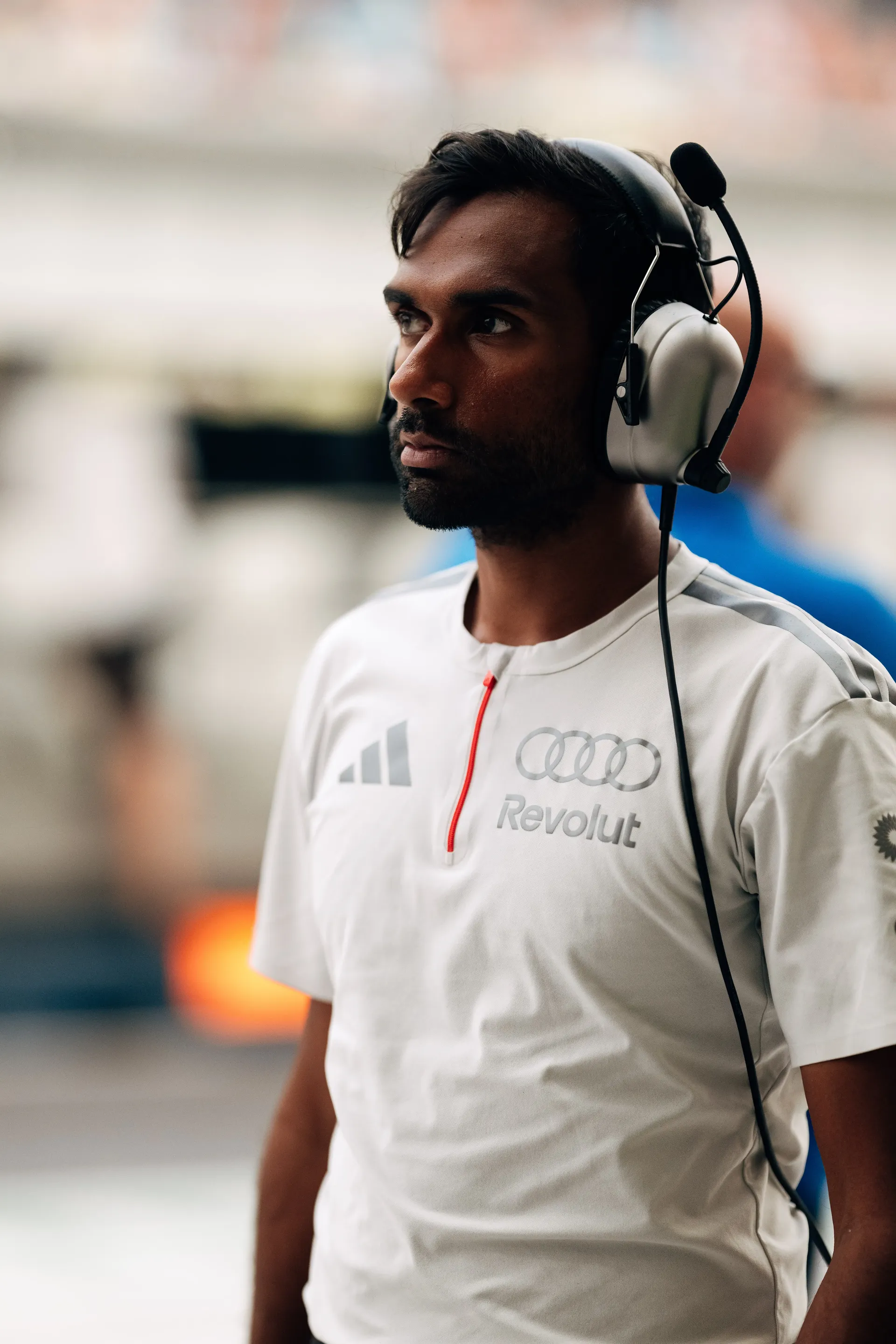 Audi Revolut F1® Team engineer in a white team shirt wearing a headset in the garage.
