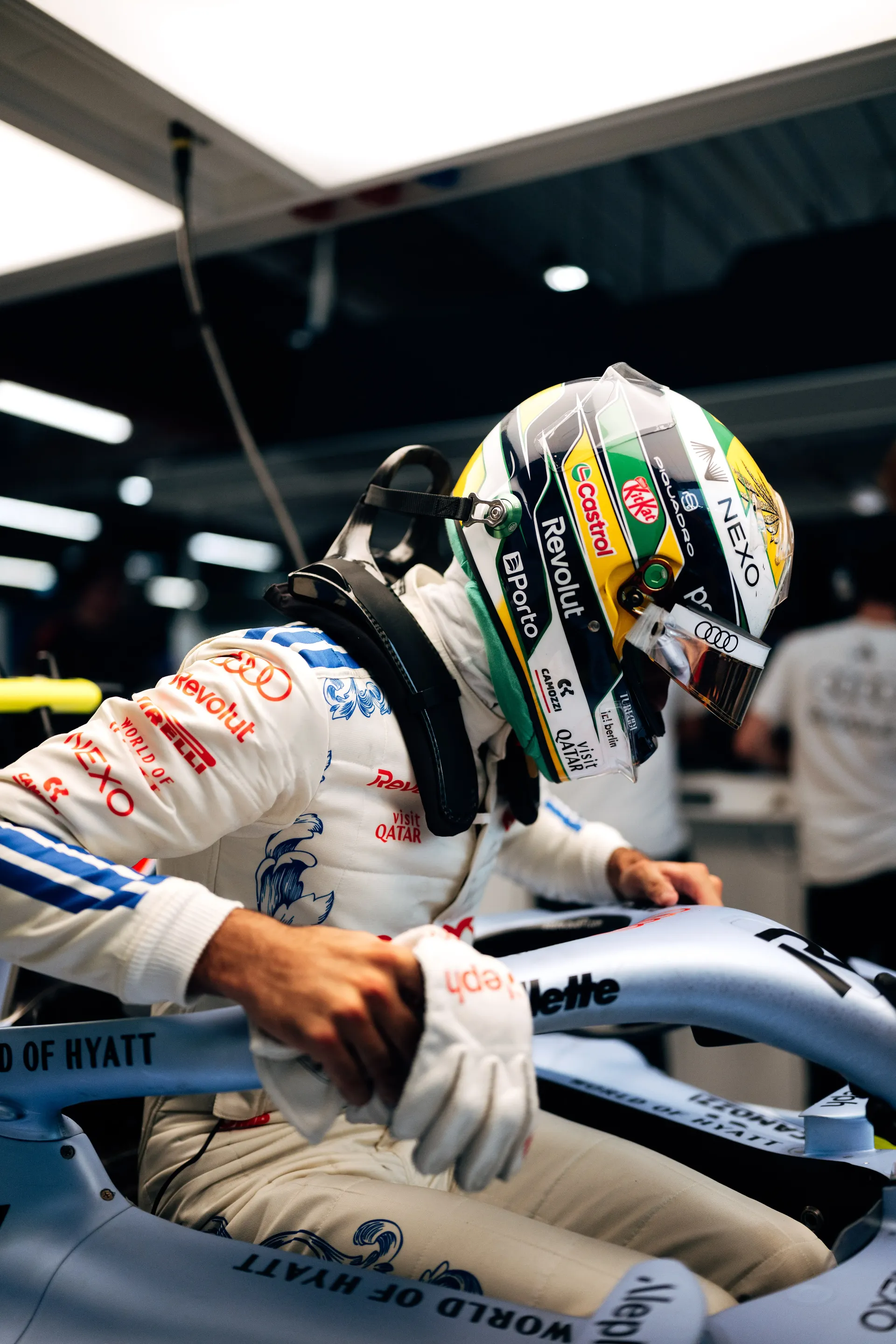 Gabriel Bortoleto in his green and yellow helmet climbing into the cockpit of the Audi Revolut F1® Team car.
