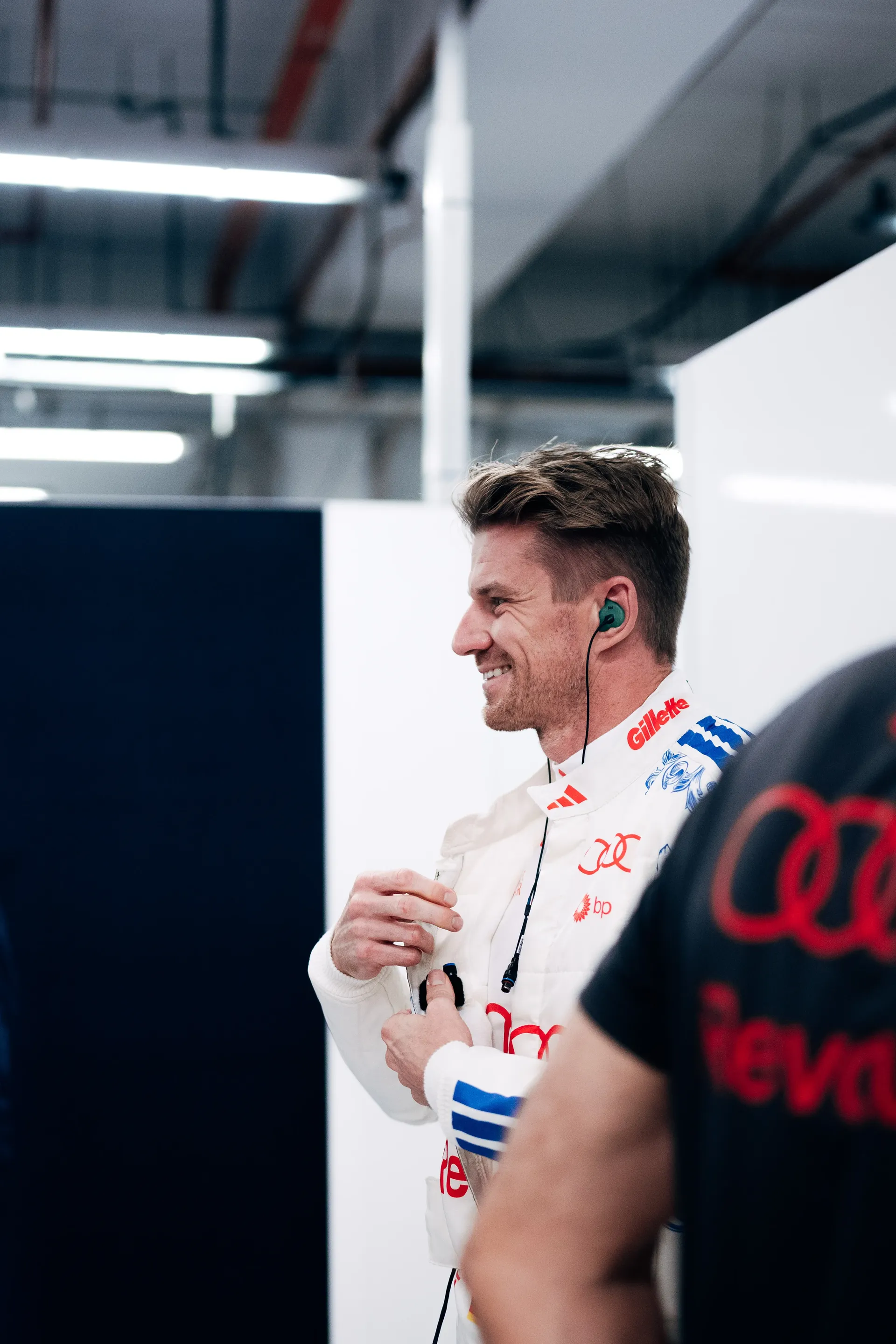 Nico Hulkenberg in race suit smiling in the Audi Revolut F1® Team garage.