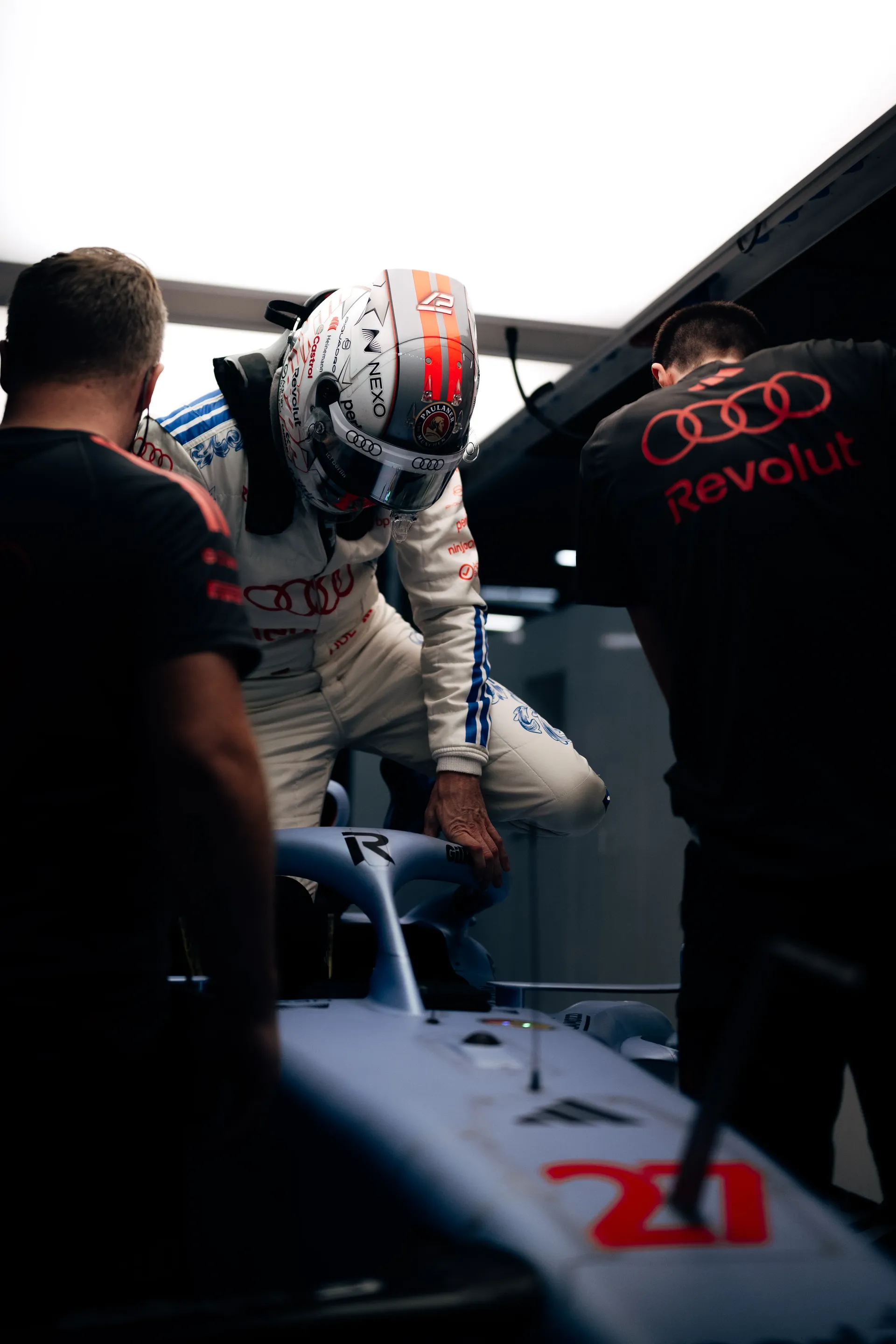 Nico Hulkenberg climbing into the car R26, assisted by Audi Revolut F1® Team mechanics.