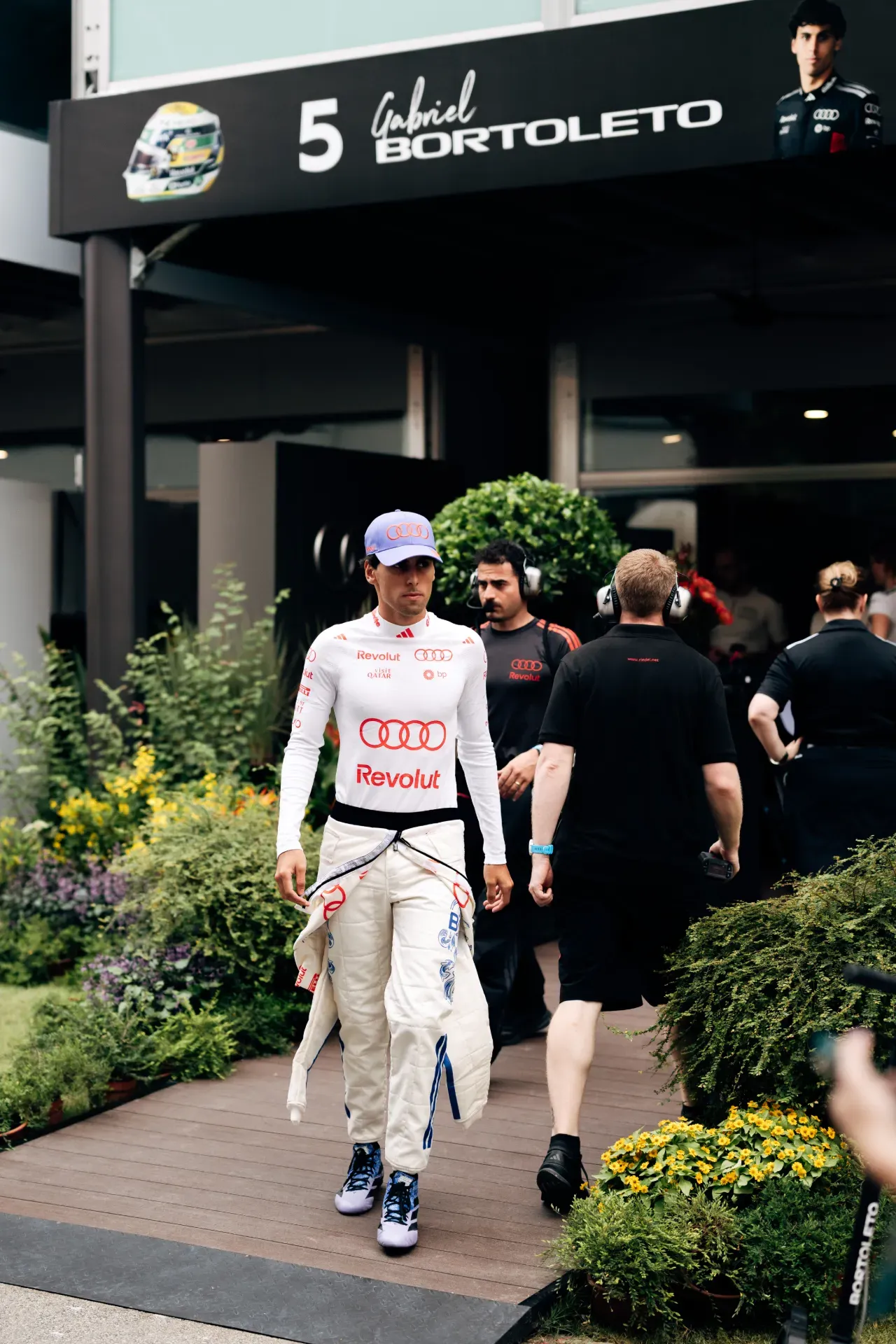 Driver Gabriel Bortoleto of the Audi Revolut F1® Team walks past team members below his name sign in Singapore