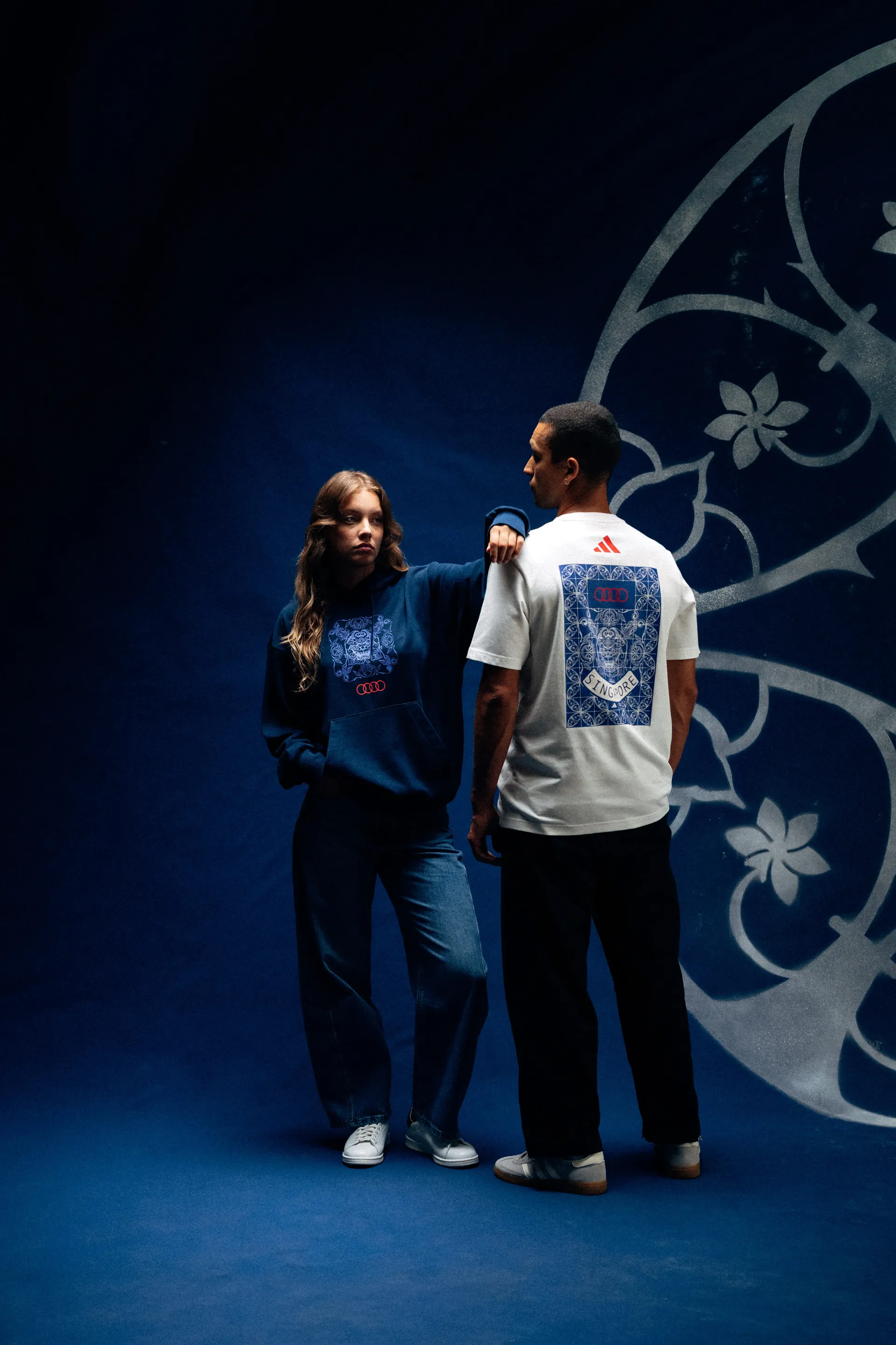 Two models wearing Audi Revolut F1® Team hoodie and tee, one resting a hand on the other's shoulder