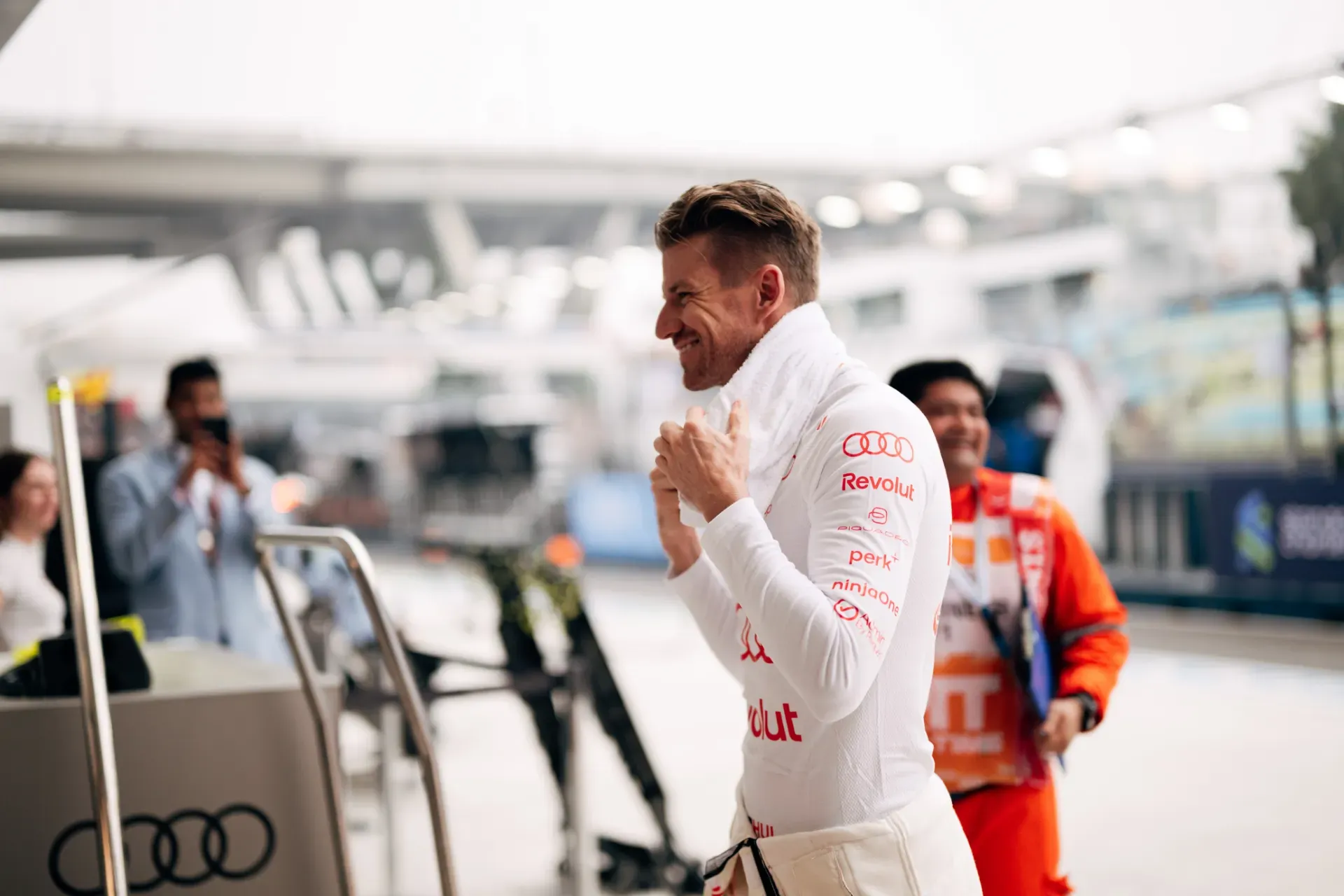 Nico Hulkenberg of the Audi Revolut F1® Team in a white race suit holding a towel at his neck in the pit lane in Singapore