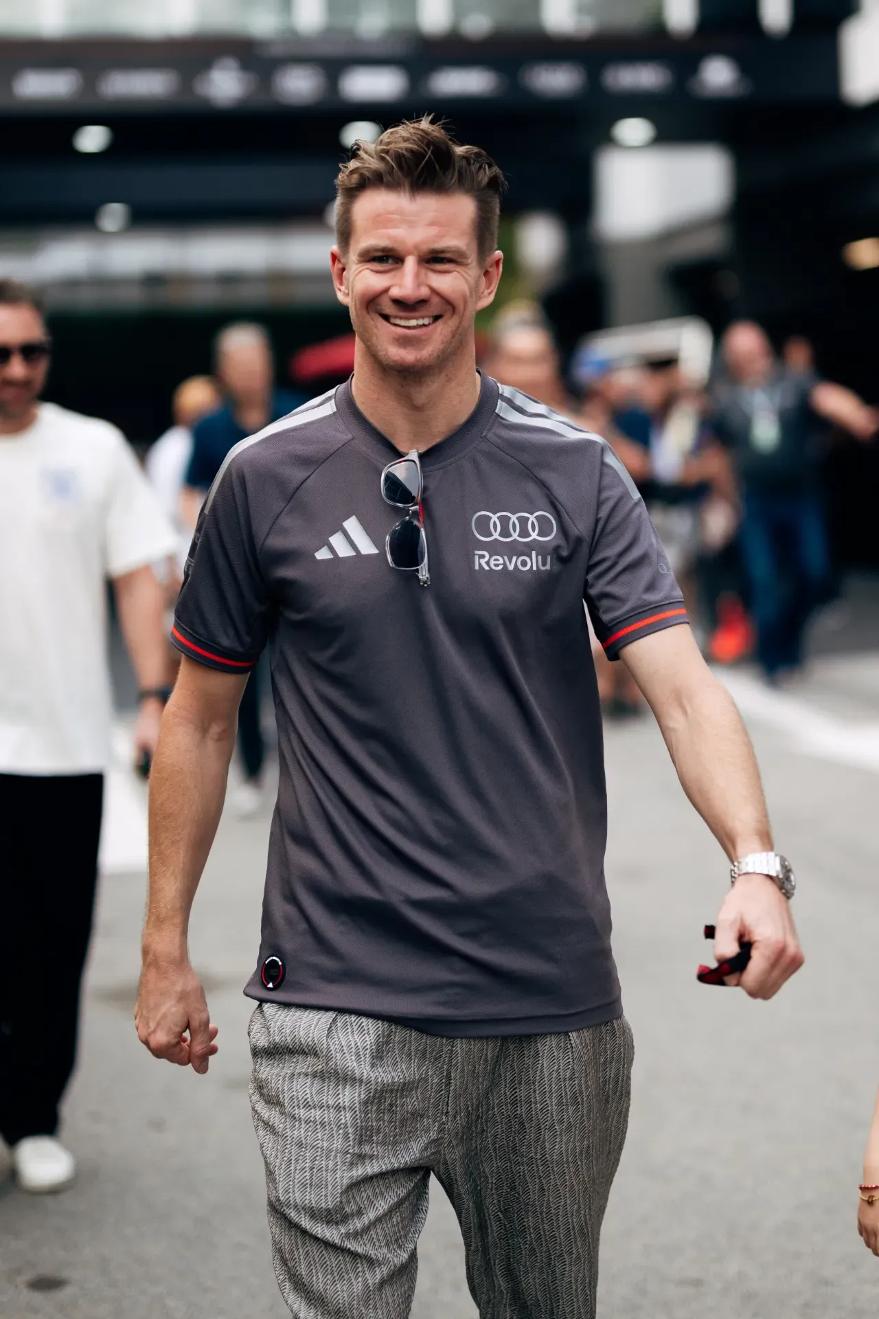 Nico Hulkenberg of the Audi Revolut F1® Team in a grey team shirt with sunglasses on the collar walks in Singapore