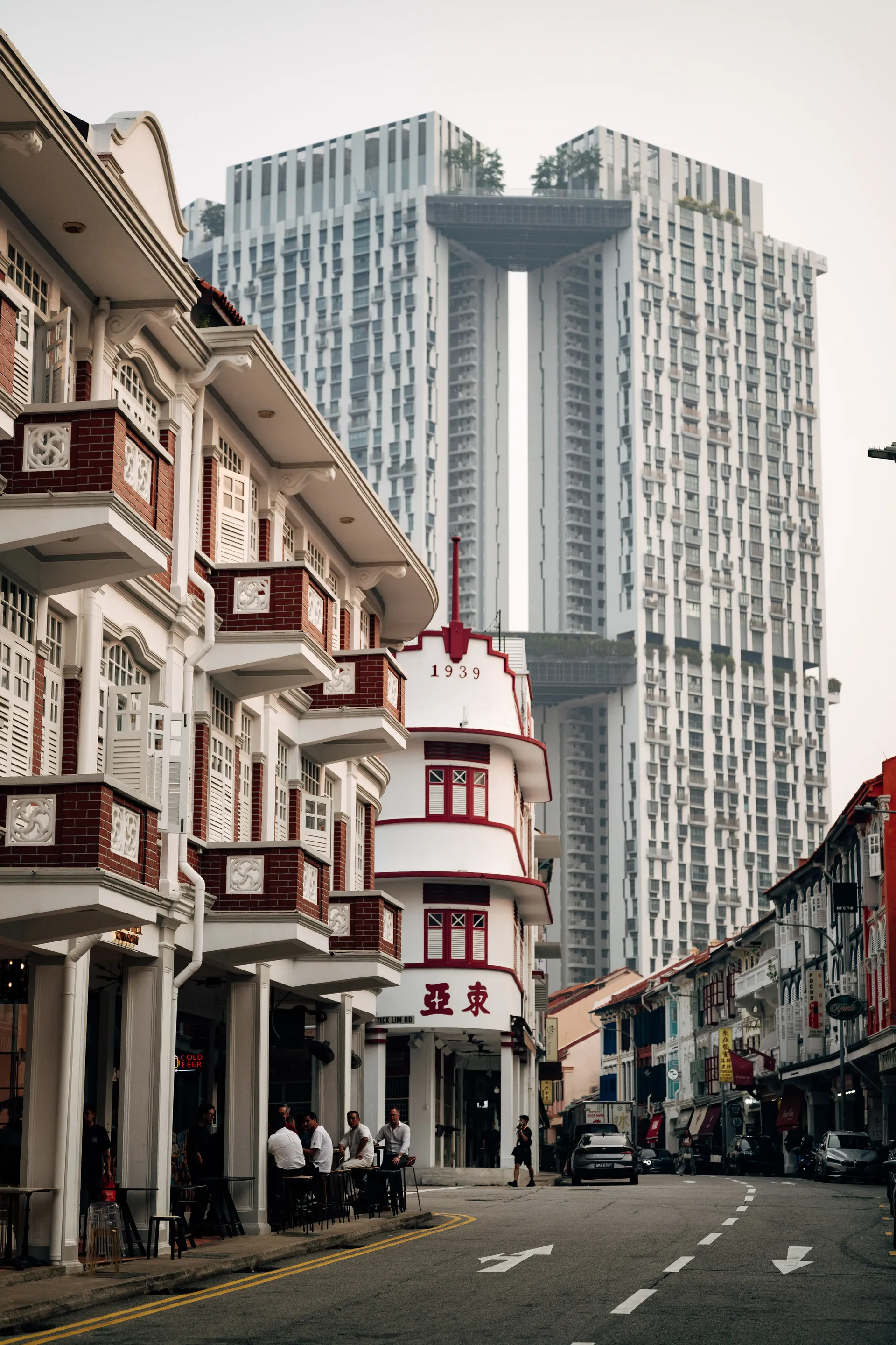 Singapore street with traditional shophouses and a modern high-rise building