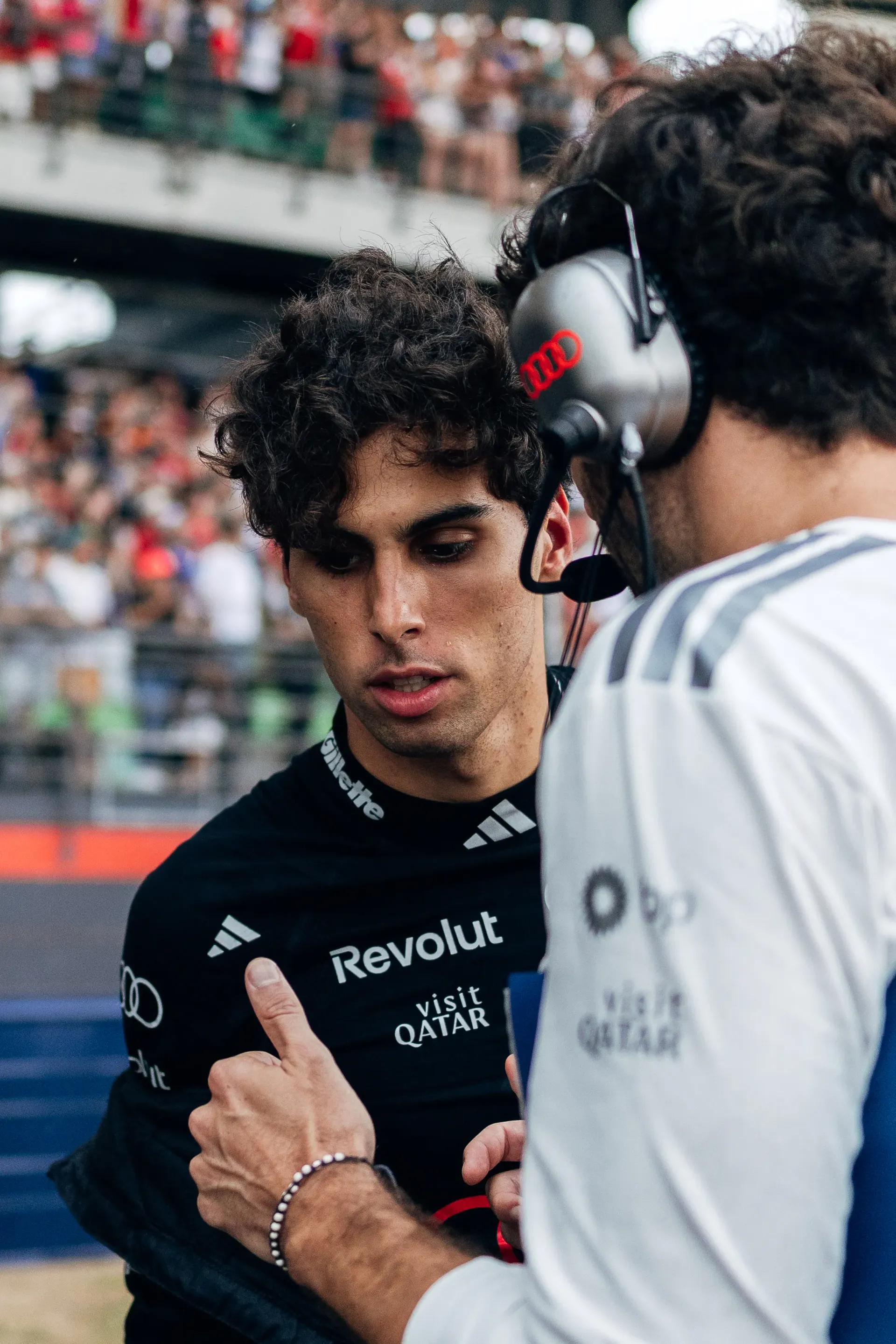 Audi Revolut F1® Team driver Gabriel Bortoleto speaks to team engineeer inside the paddock