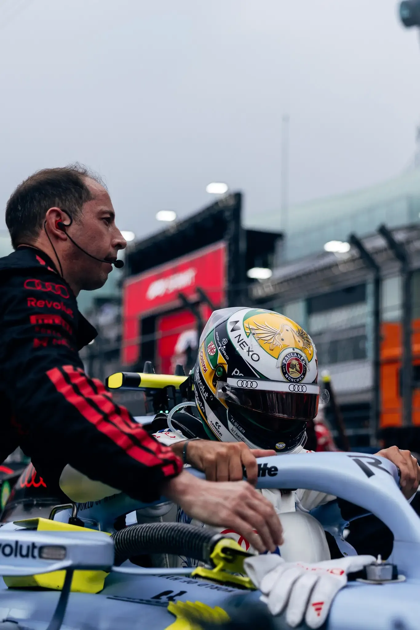 Audi Revolut F1® Team mechanic helping driver Gabriel Bortoleto into the cockpit.