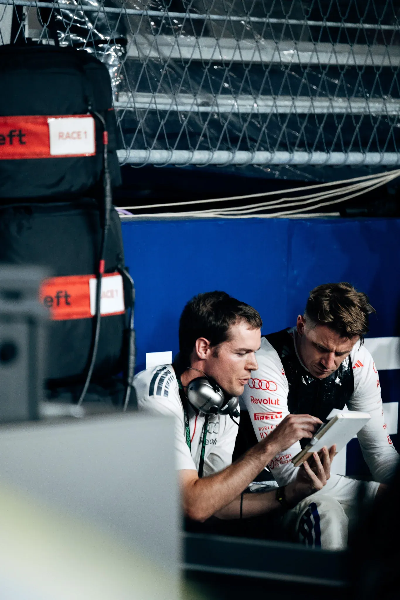 Audi Revolut F1® Team driver Nico Hulkenberg reviews data on a tablet in the garage. witch engineer wearing headset