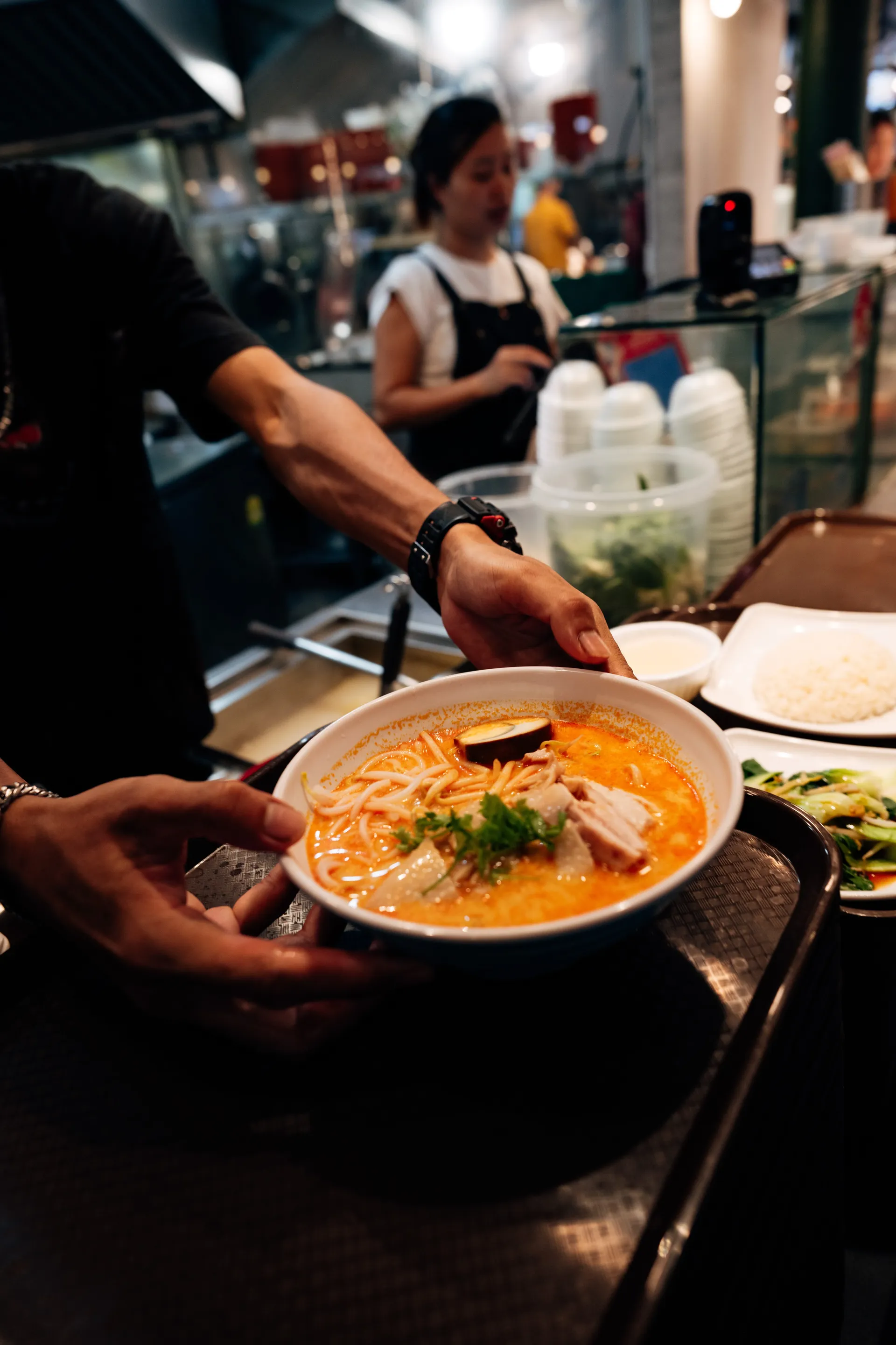 Bowl of laksa with noodles, chicken, egg and coriander placed on a tray at Take Laksa in Singapore