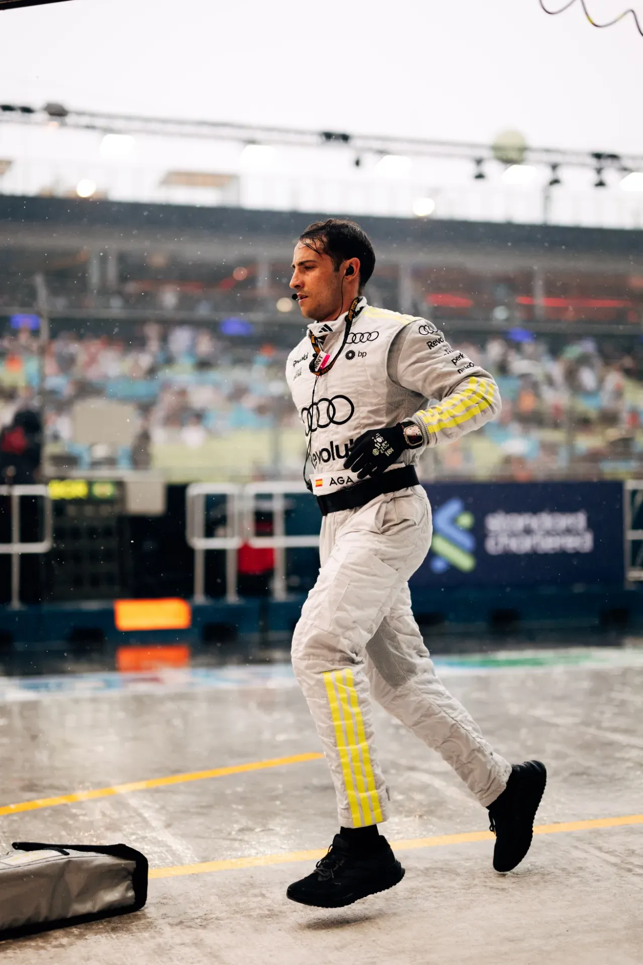 Team member of the Audi Revolut F1® Team in silver overalls running across the wet pit lane in Singapore