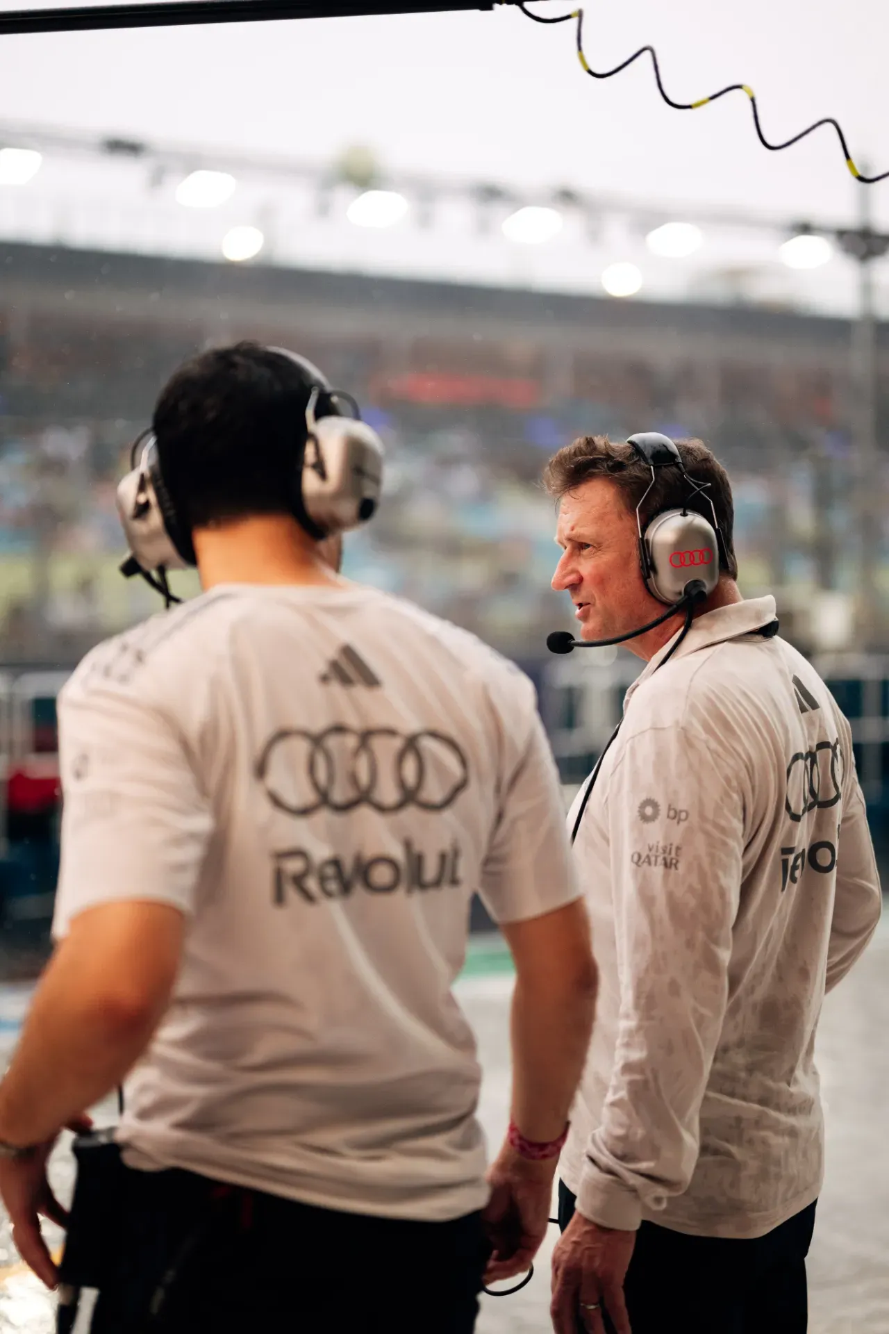 Two team members of the Audi Revolut F1® Team wearing headsets and talking in the pit lane in Singapore