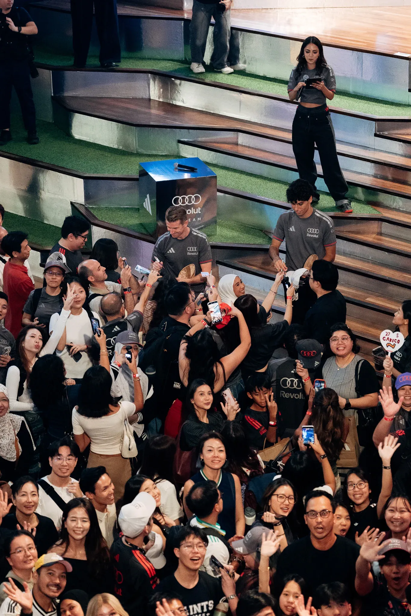 Large crowd gathered on indoor steps, watching an event.