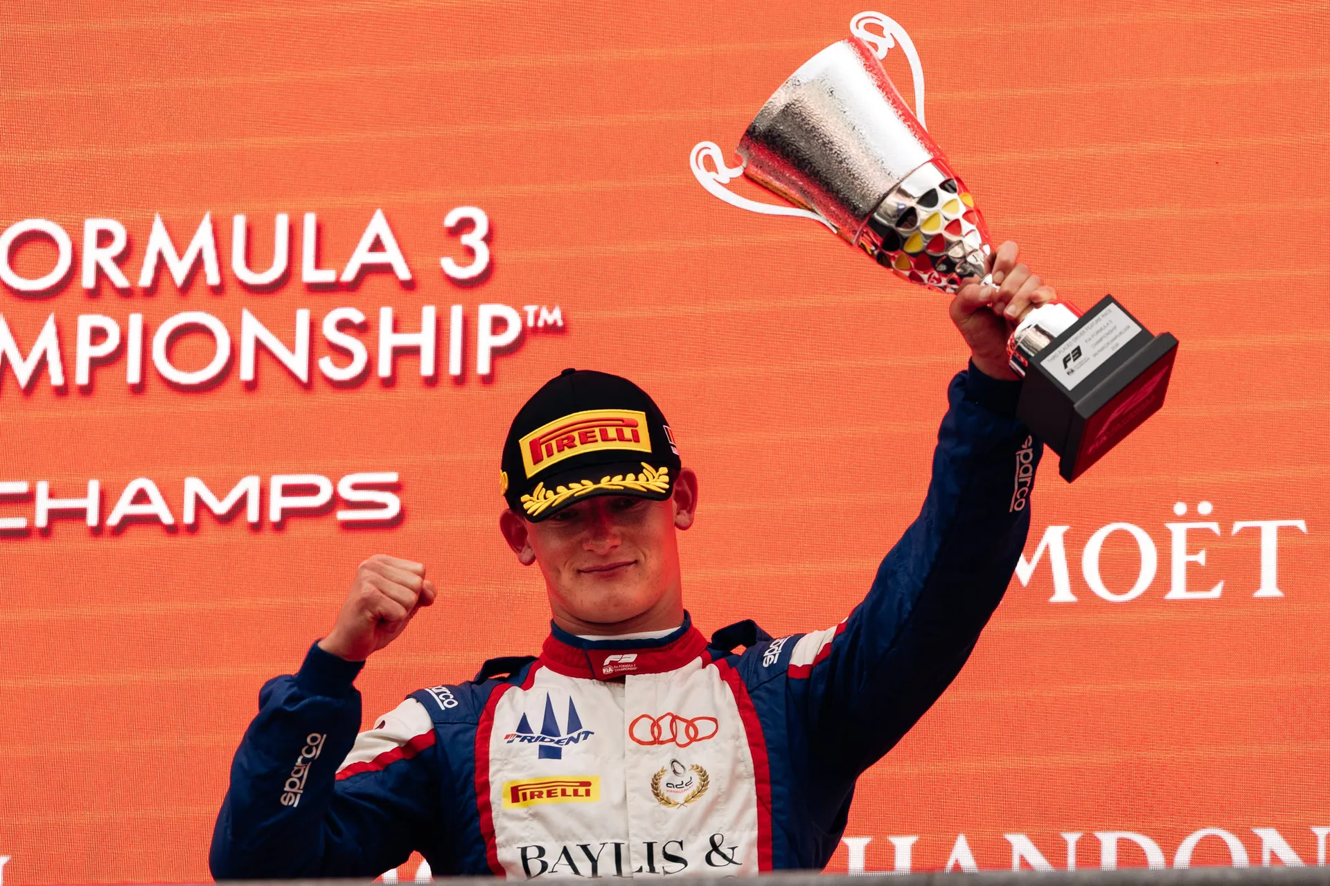 Freddie Slater raising his trophy on the podium at Spa-Francorchamps
