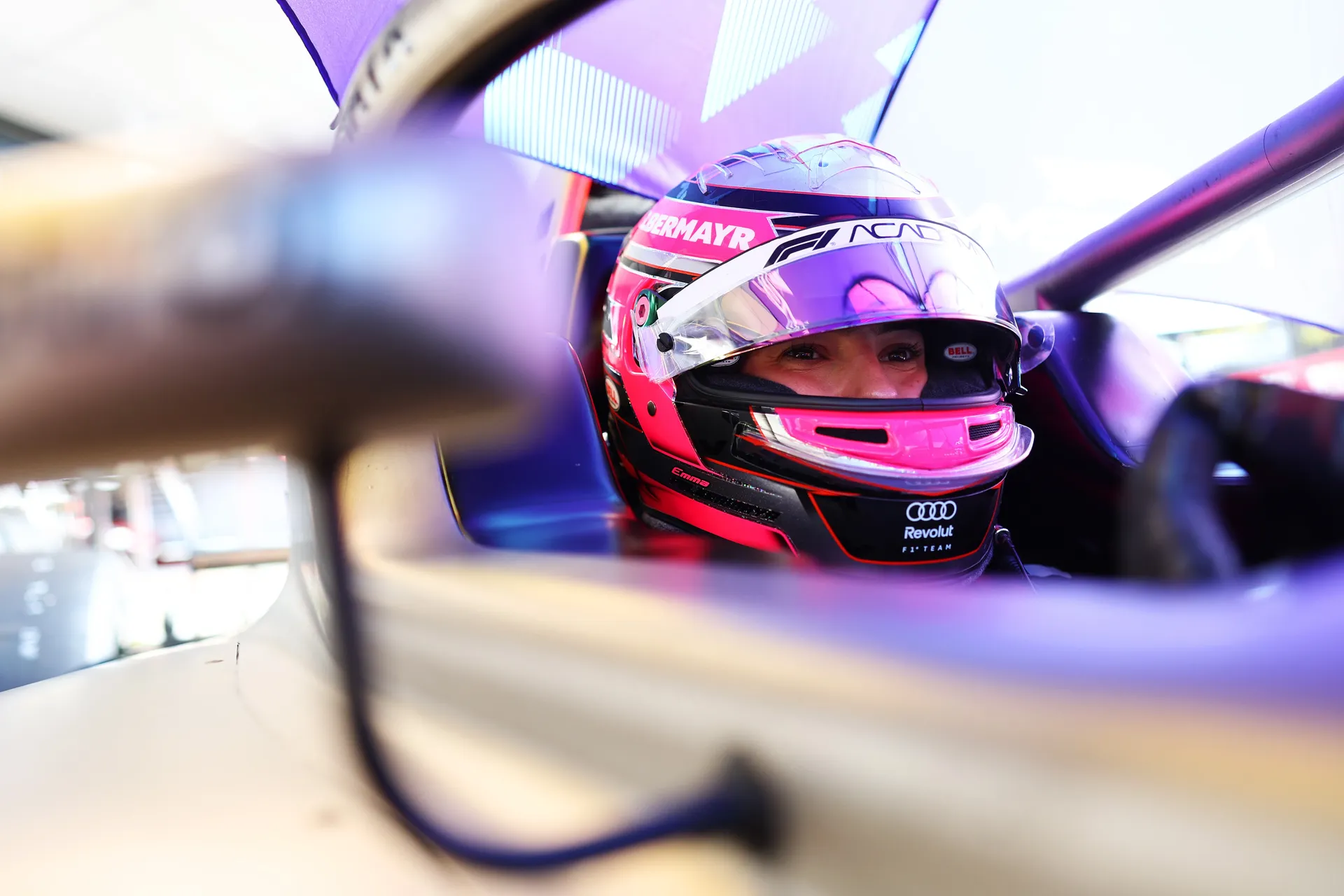 Emma Felbermayr in the cockpit wearing her helmet, captured mid-focus as she prepares to head out on track for F1 Academy at Silverstone.