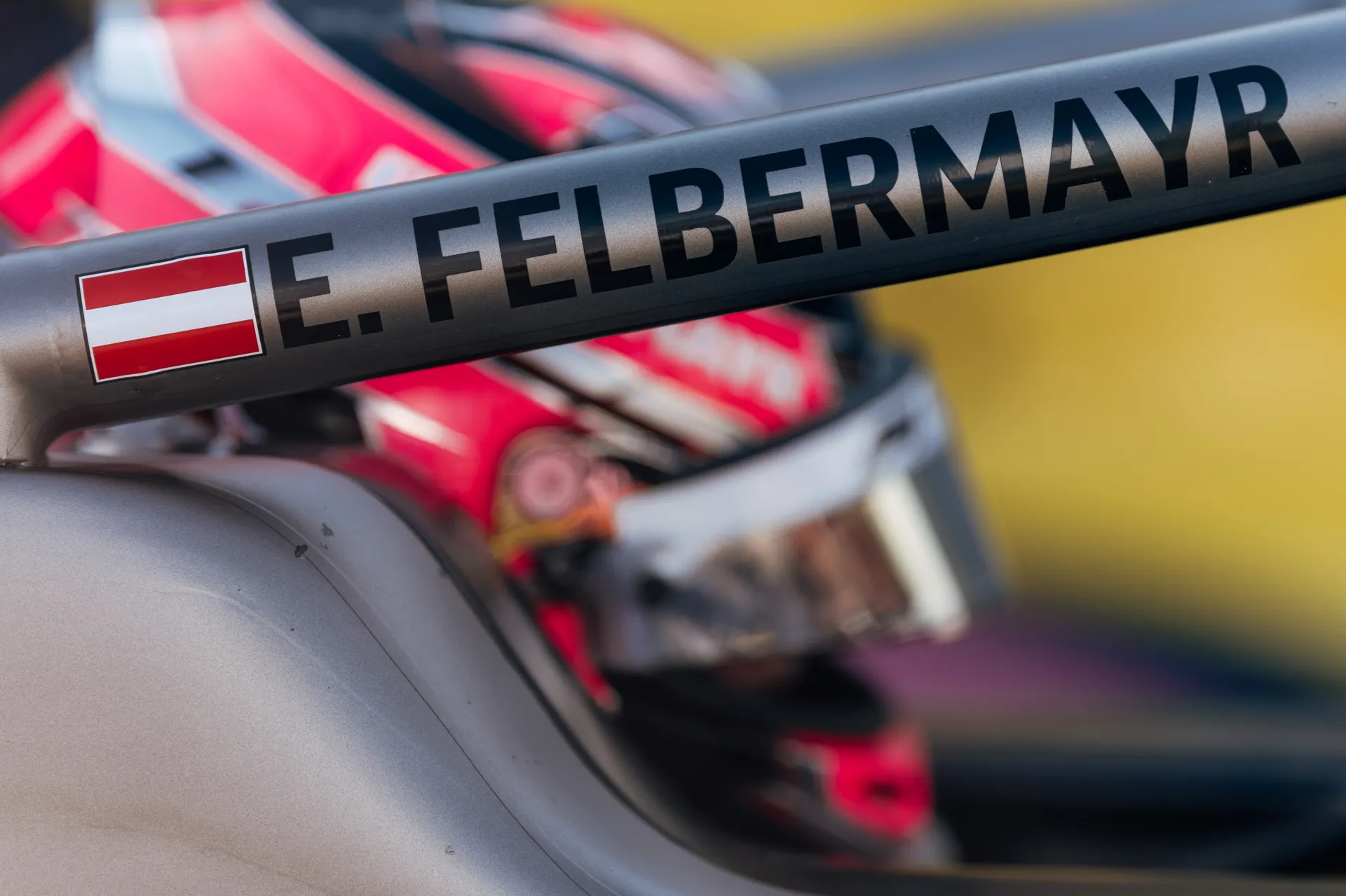 Close-up of the cockpit halo displaying Emma Felbermayr’s name and Austrian flag, with her helmet visible in the background.