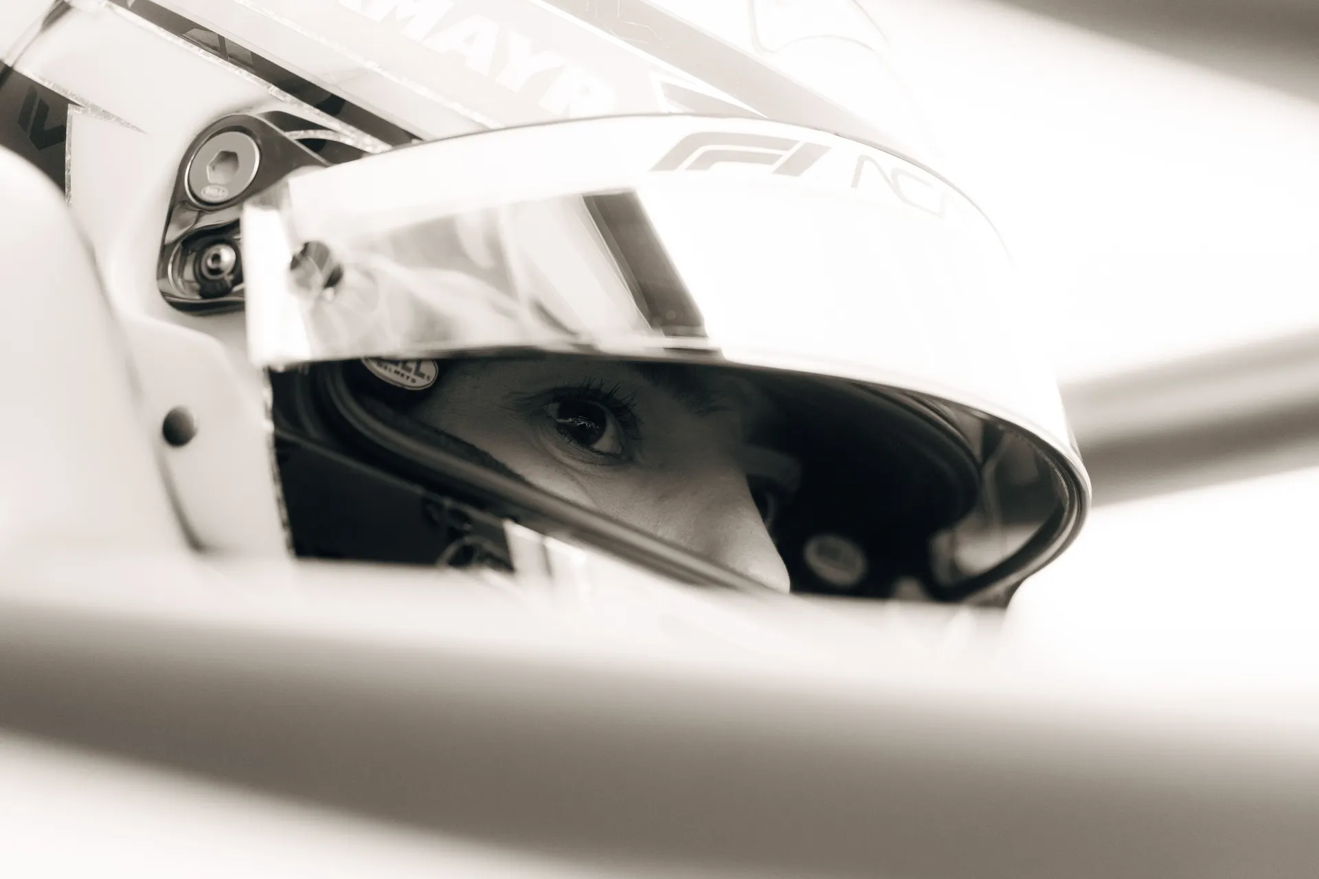 High-contrast close-up of a driver’s eye behind a helmet visor inside the cockpit, highlighting focus and concentration.