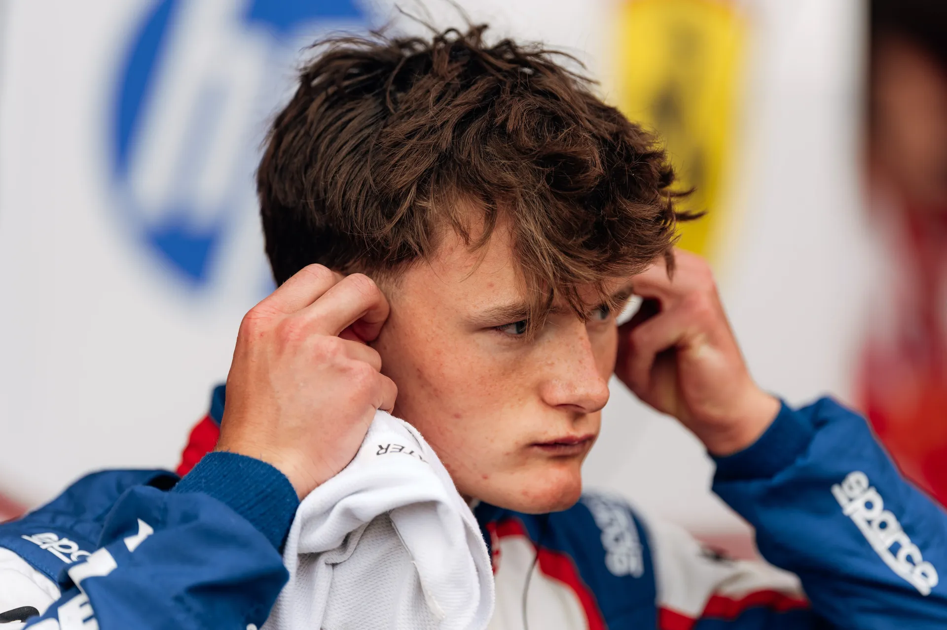 Close-up of Freddie Slater adjusting his earpieces and balaclava, fully focused before entering the car for his F3 session.