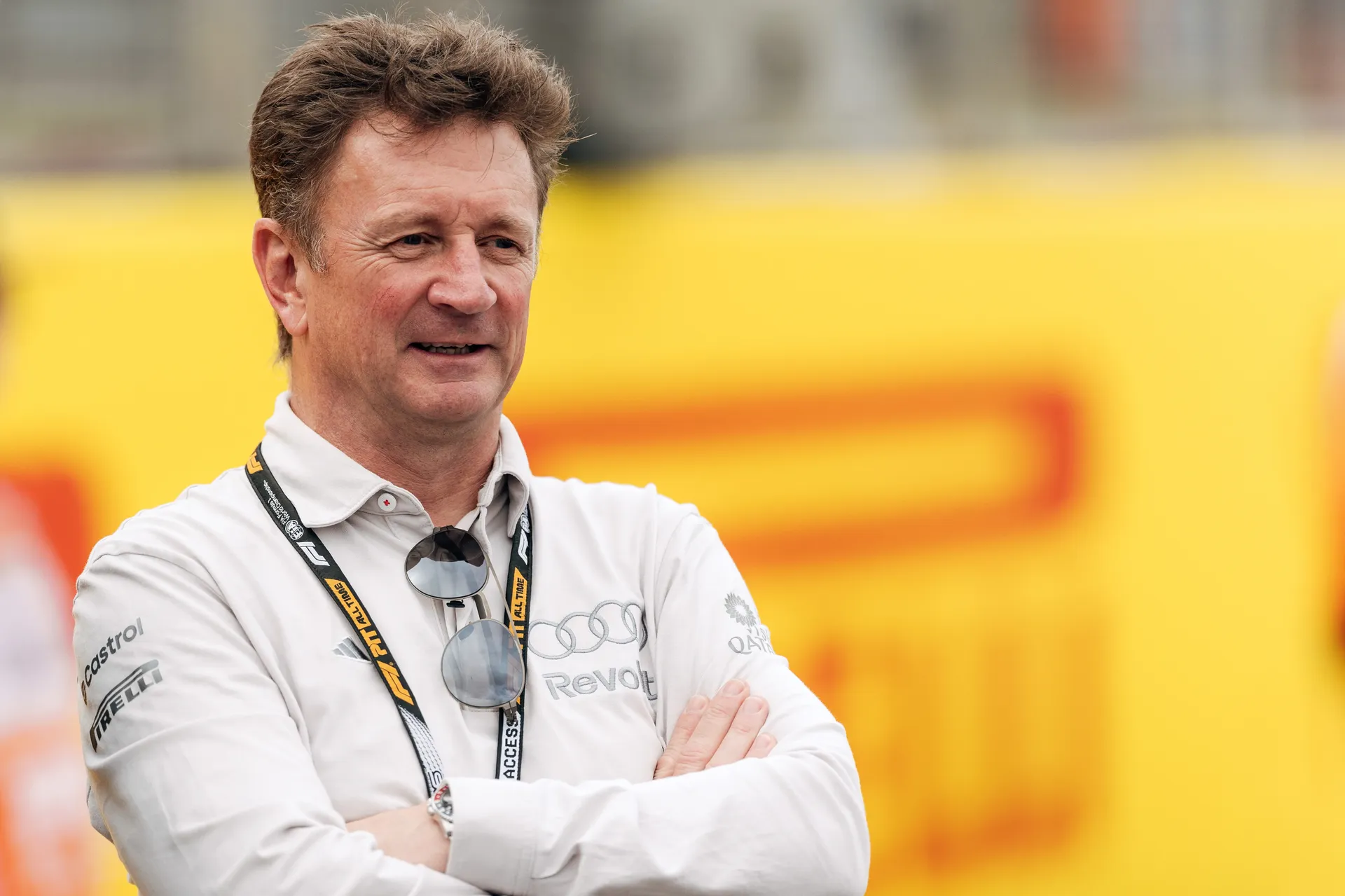 Allan McNish, Racing Director of Audi Revolut F1® Team, stands trackside with arms crossed, observing preparations at Silverstone.