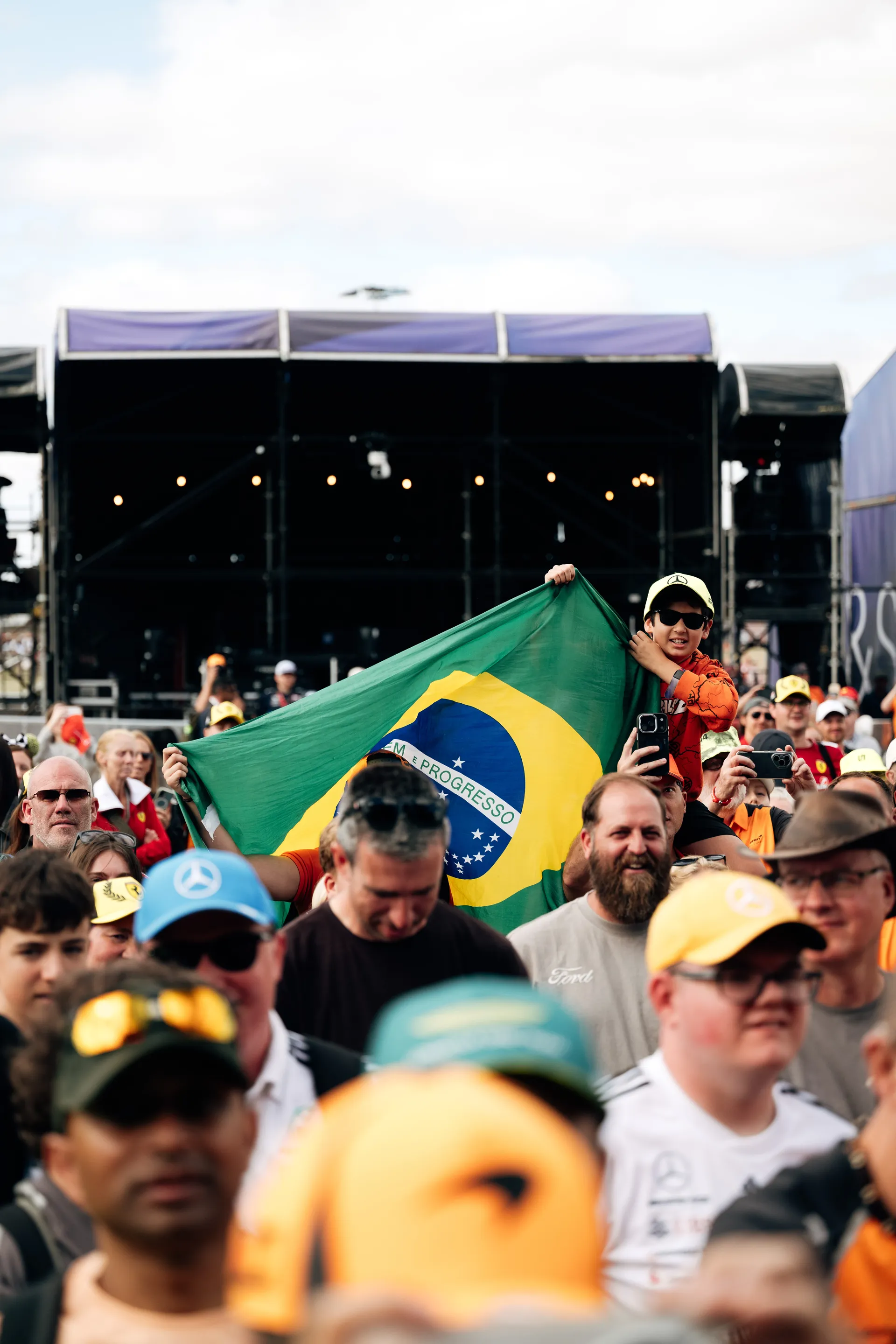 Fans in a packed crowd hold up a large Brazilian flag during the Audi Revolut F1® Team fan forum at the British Grand Prix.