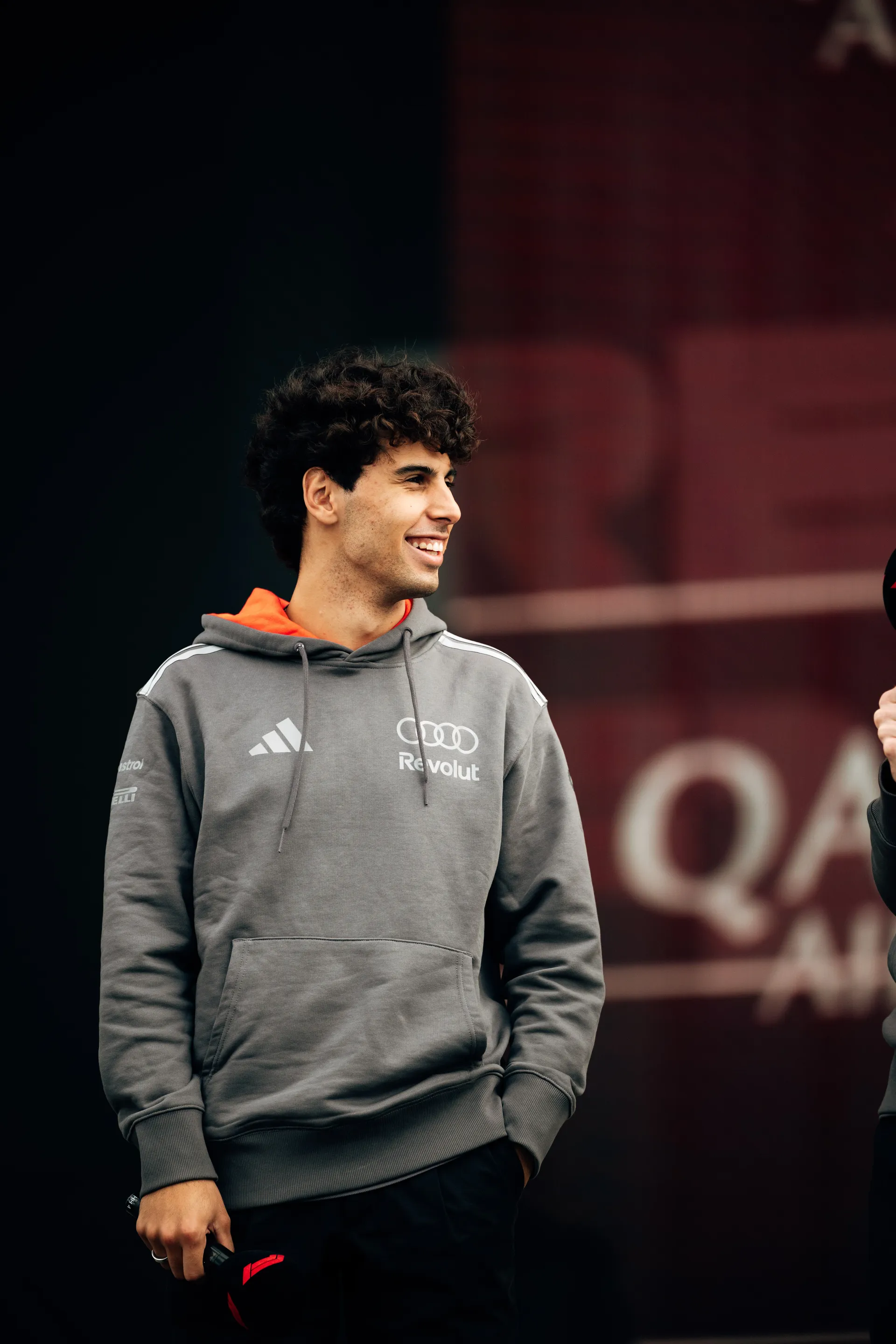 Gabriel Bortoleto smiles on stage holding a microphone while interacting with fans at the Audi Revolut F1® Team fan forum.
