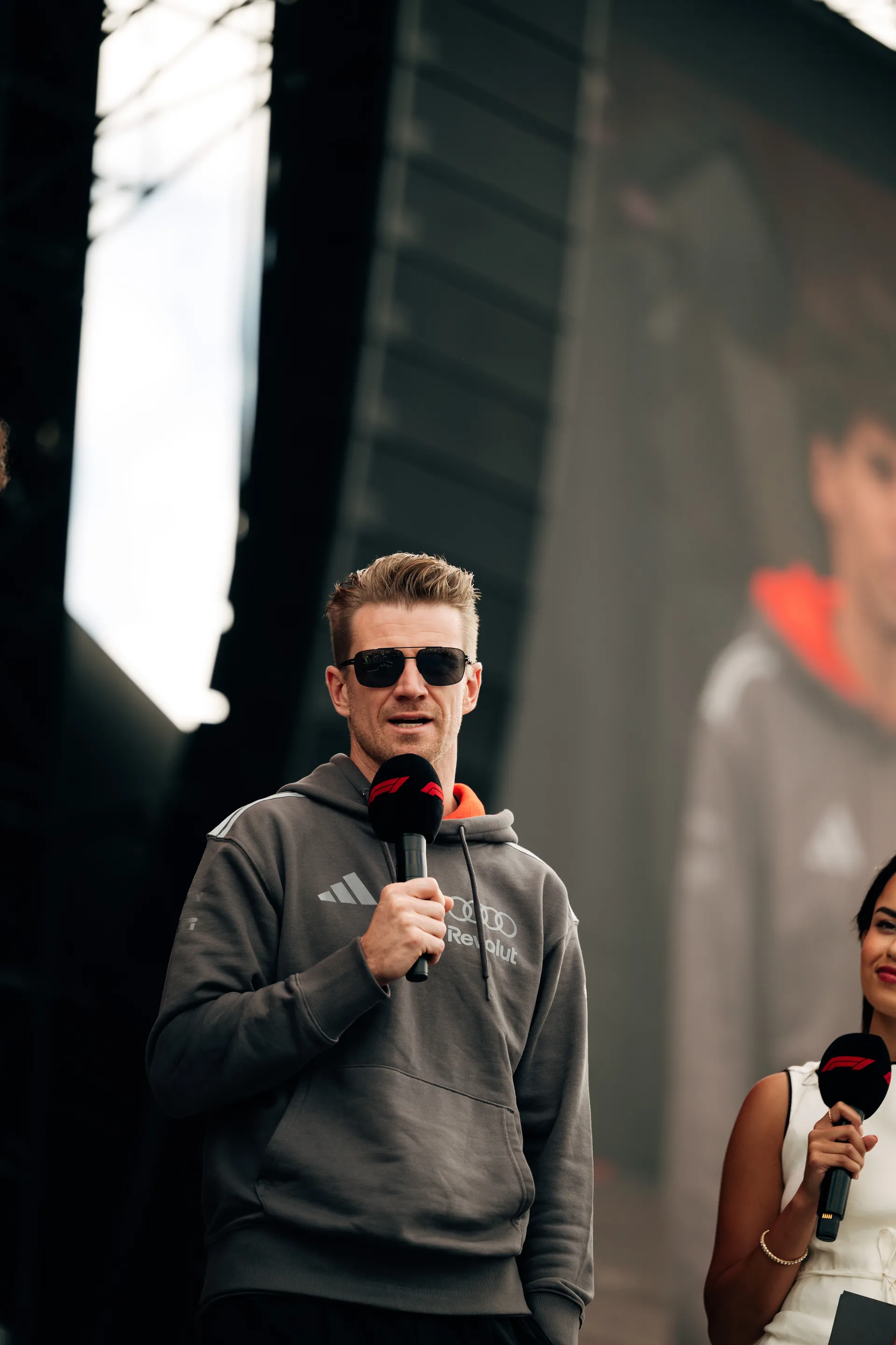 Nico Hulkenberg addresses the crowd on stage with a microphone at the Audi Revolut F1® Team fan forum.
