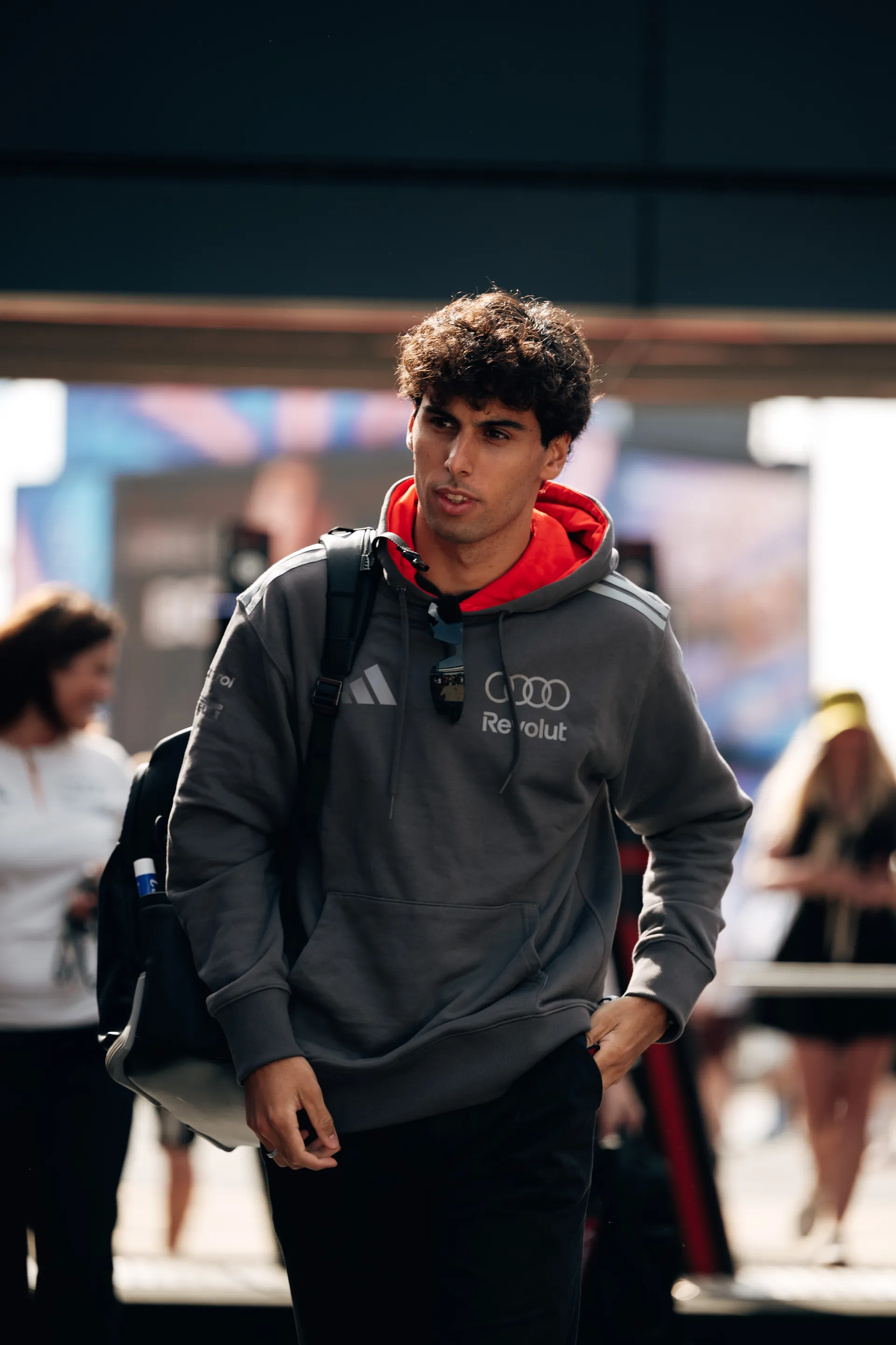 Gabriel Bortoleto arrives in the paddock on Friday at Silverstone, wearing Audi Revolut F1® Team kit and carrying a backpack, making his way through the crowd.