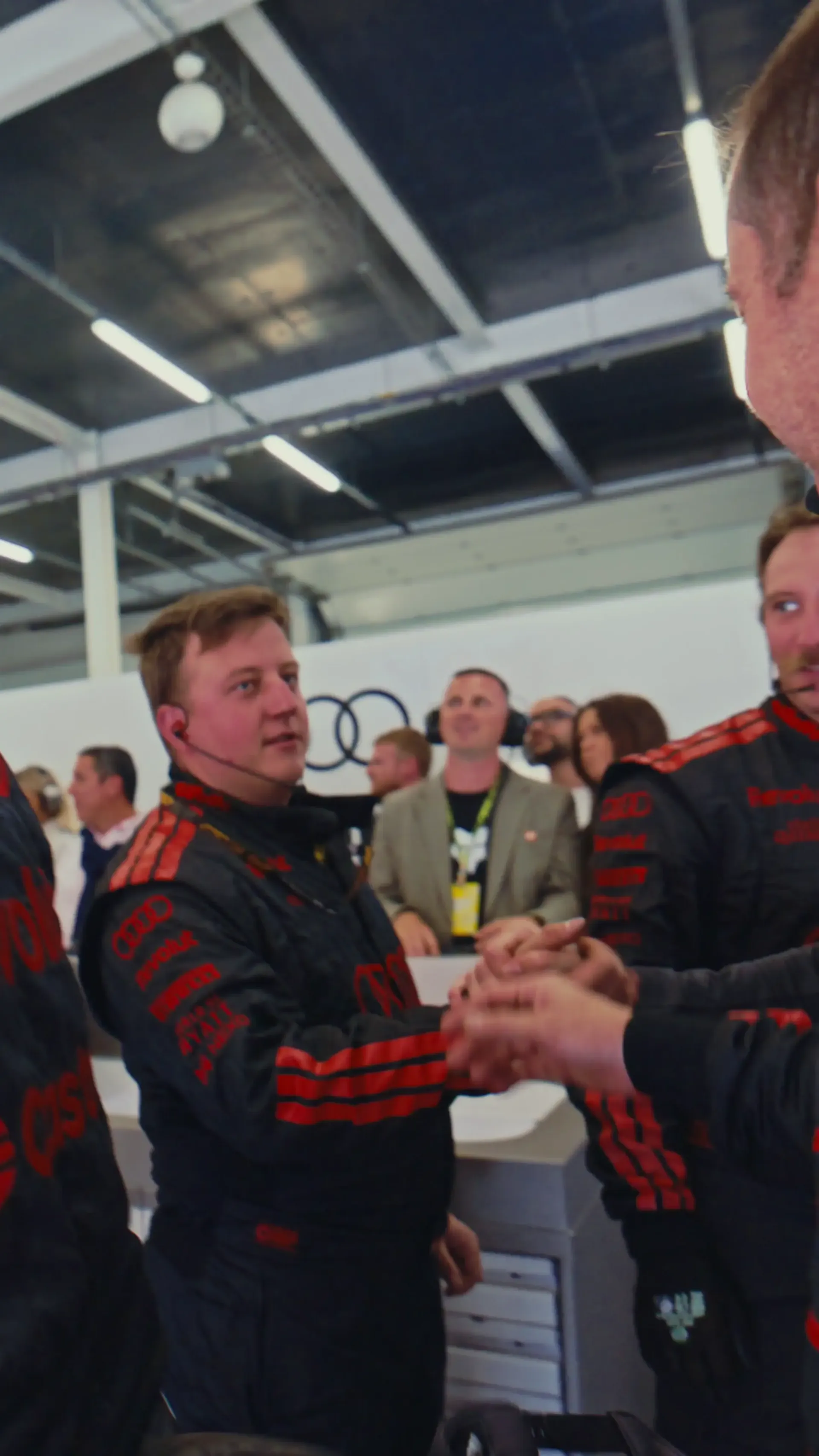 Audi Revolut F1® Team members celebrate together in the garage after the race at Silverstone, sharing a moment of relief and team spirit.
