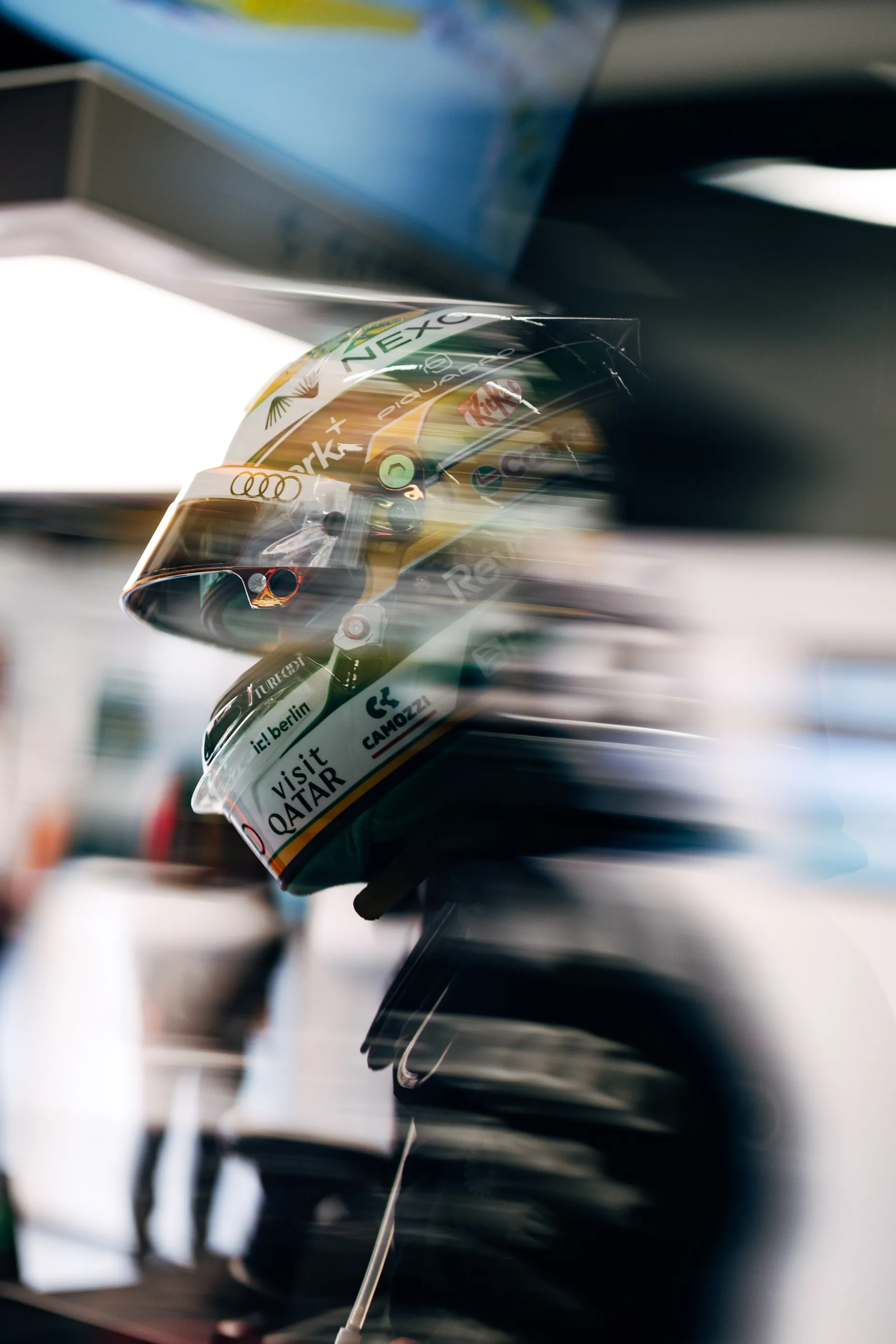 Motion-blurred shot of Gabriel Bortoleto’s helmet as team members move through the Audi Revolut F1® Team garage during the intensity of Qualifying.