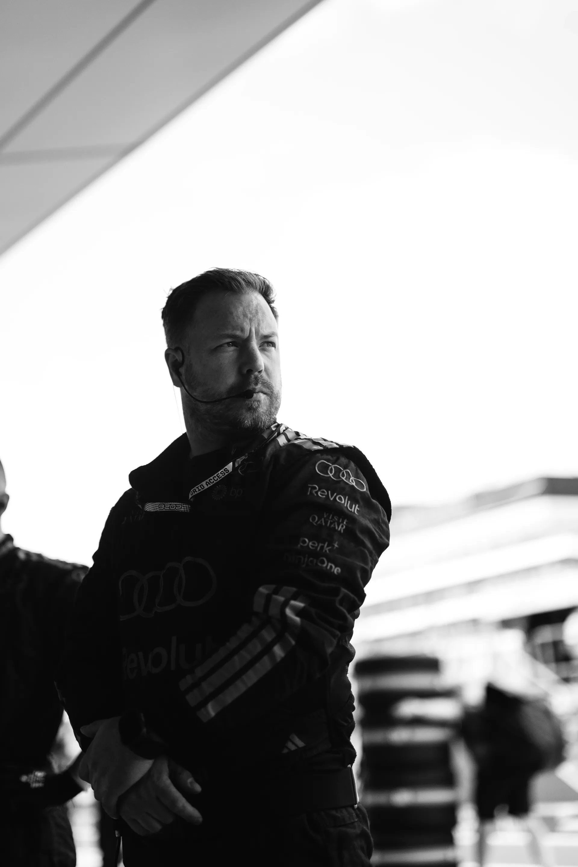 Team Member of Audi Revolut F1® Team, stands in the garage wearing a headset, observing operations during Qualifying.