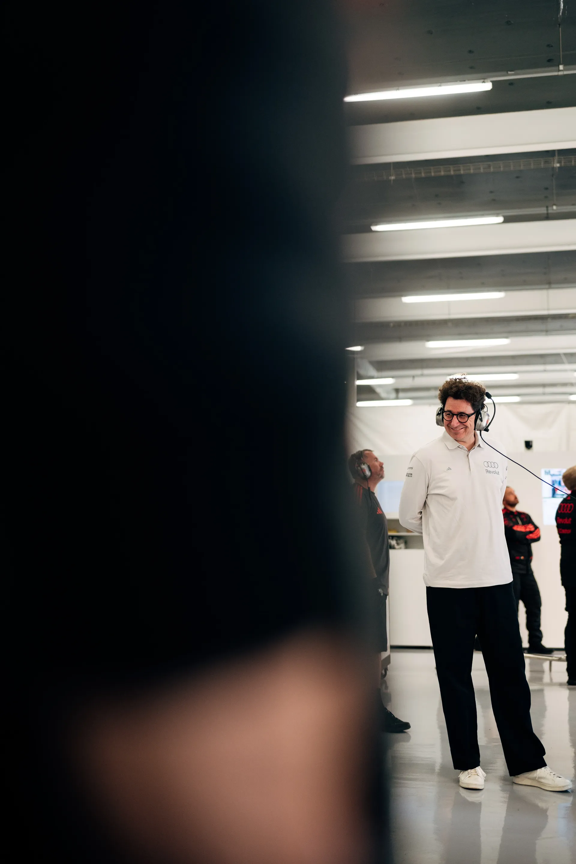 Mattia Binotto, Team Principal of Audi Revolut F1® Team, stands in the garage wearing a headset, watching data screens and team activity during Qualifying.