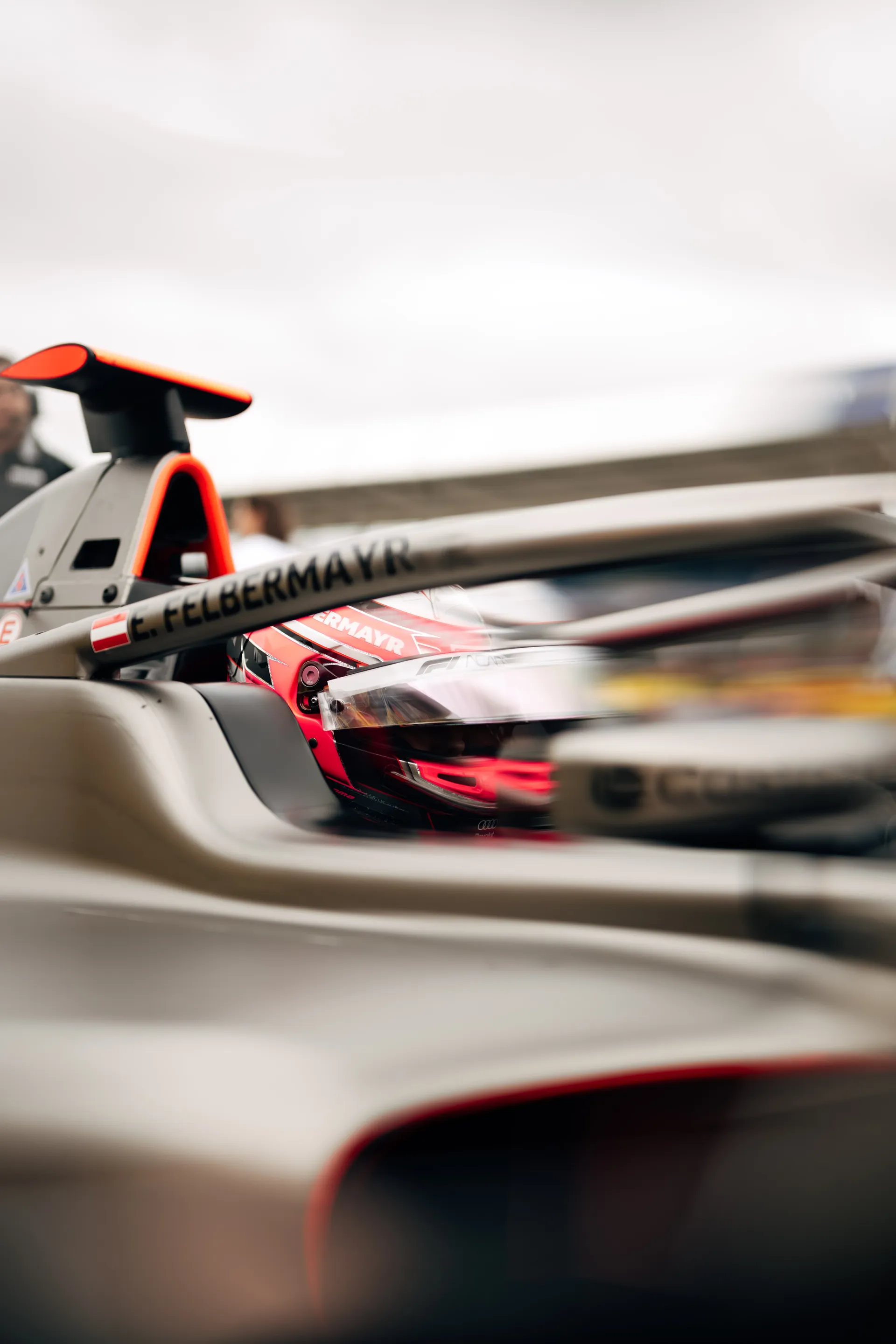 Close-up of Emma Felbermayr wearing a pink helmet inside a single-seater cockpit for Audi Revolut F1® Team, framed through the halo structure.