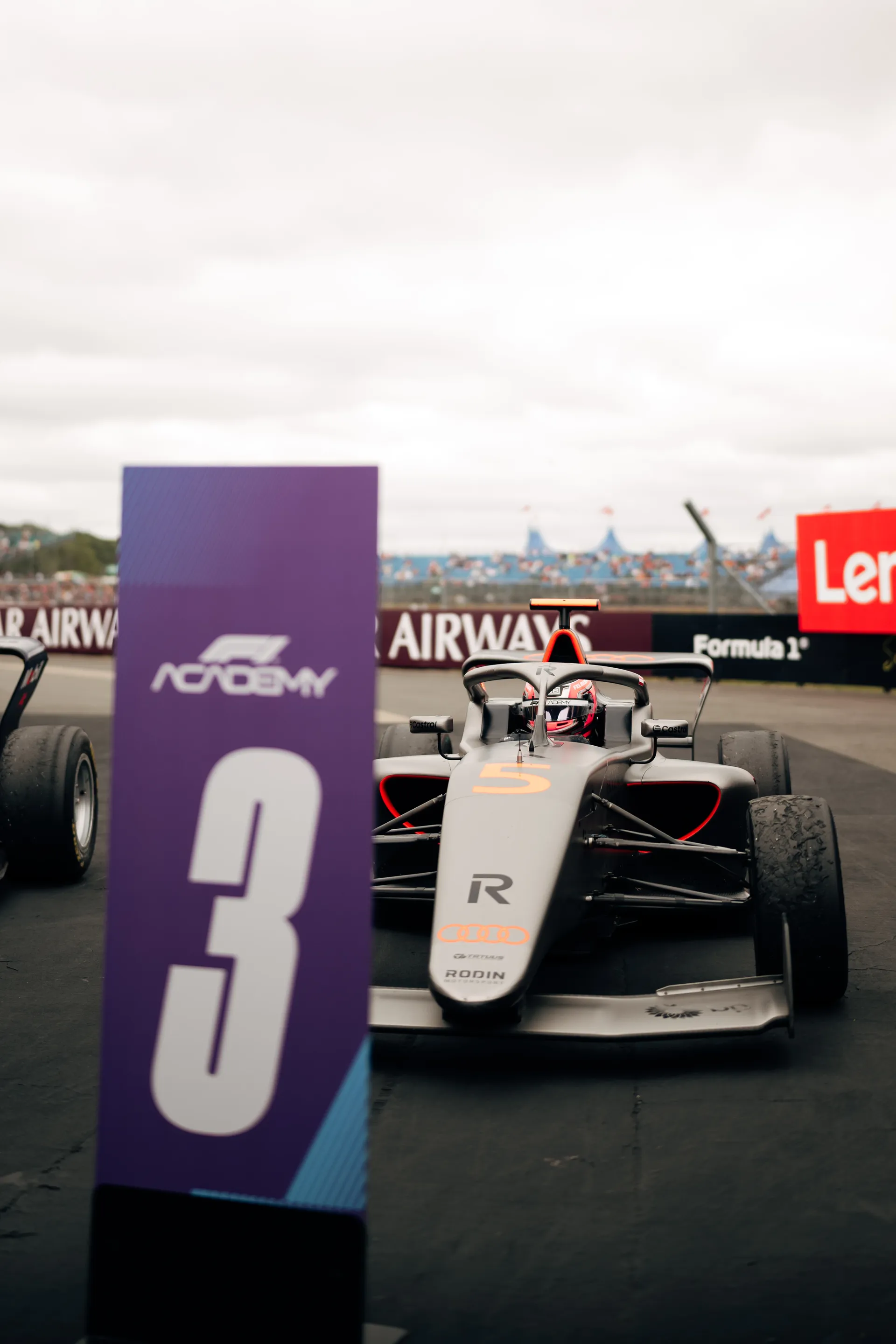 Front view of a single-seater with Emma Felbermayr seated in the cockpit on track, Audi branding visible.