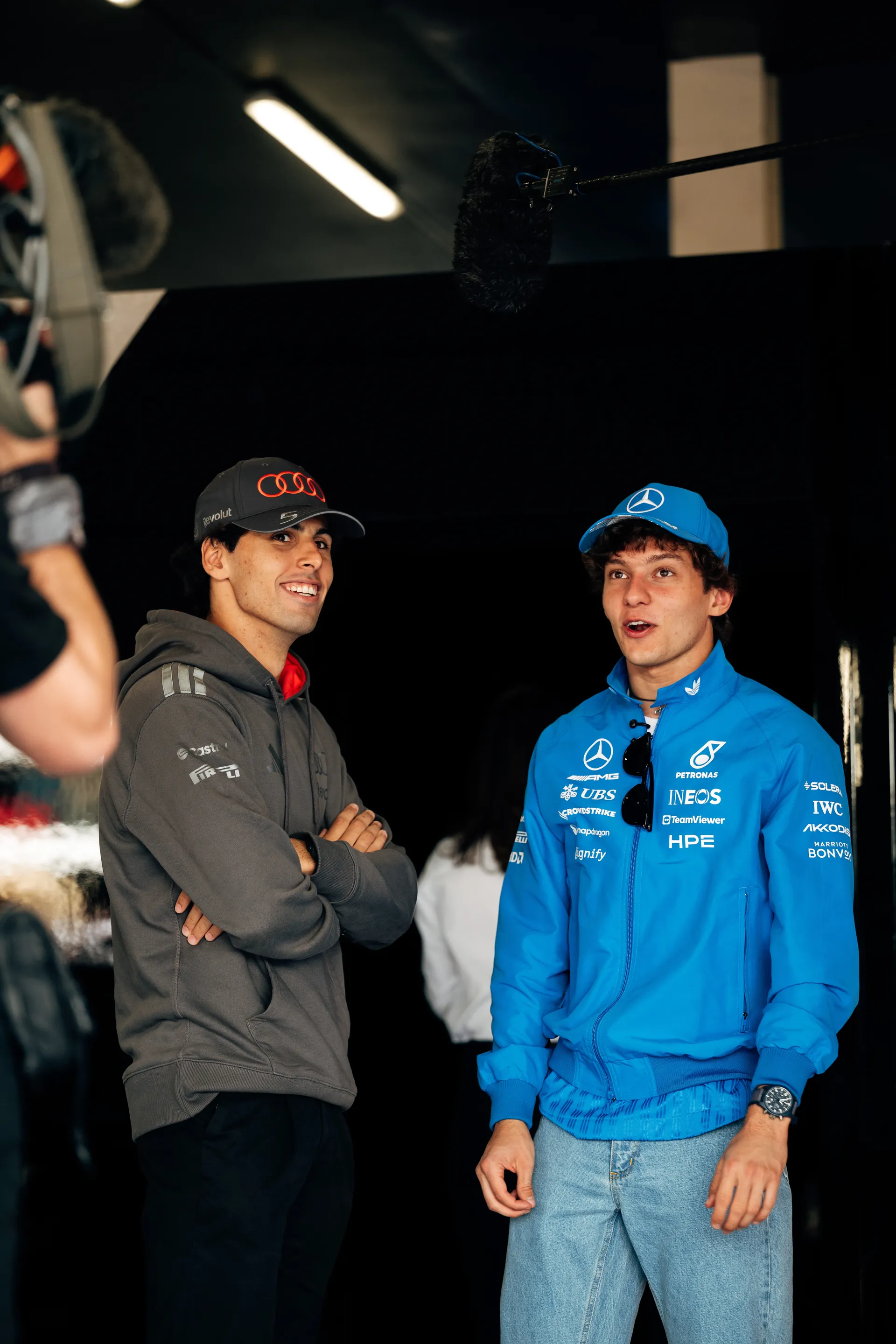 Gabriel Bortoleto speaking with another driver in the garage area during media activity at Silverstone.