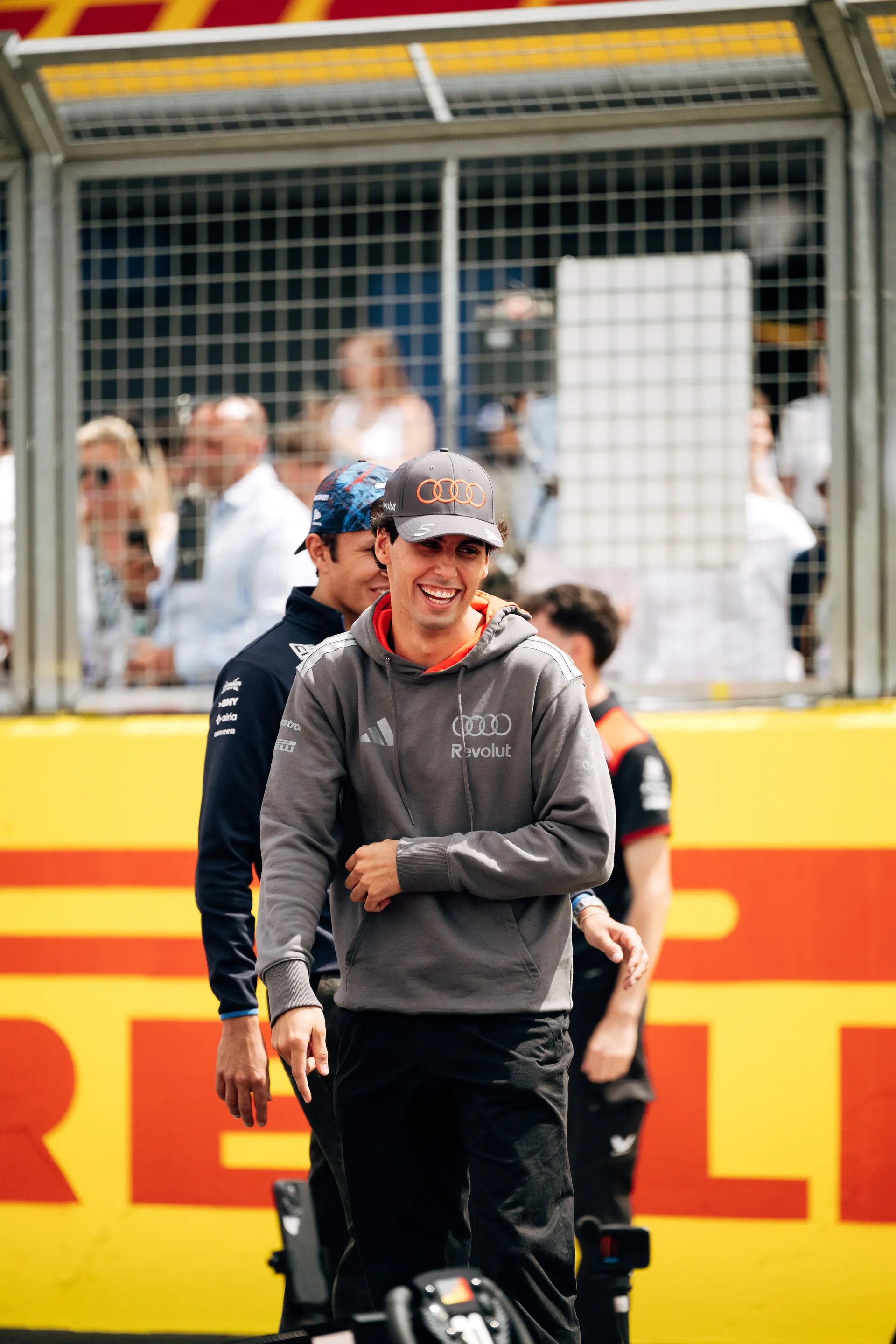 Gabriel Bortoleto smiling while walking along the paddock in Audi Revolut F1® Team kit.