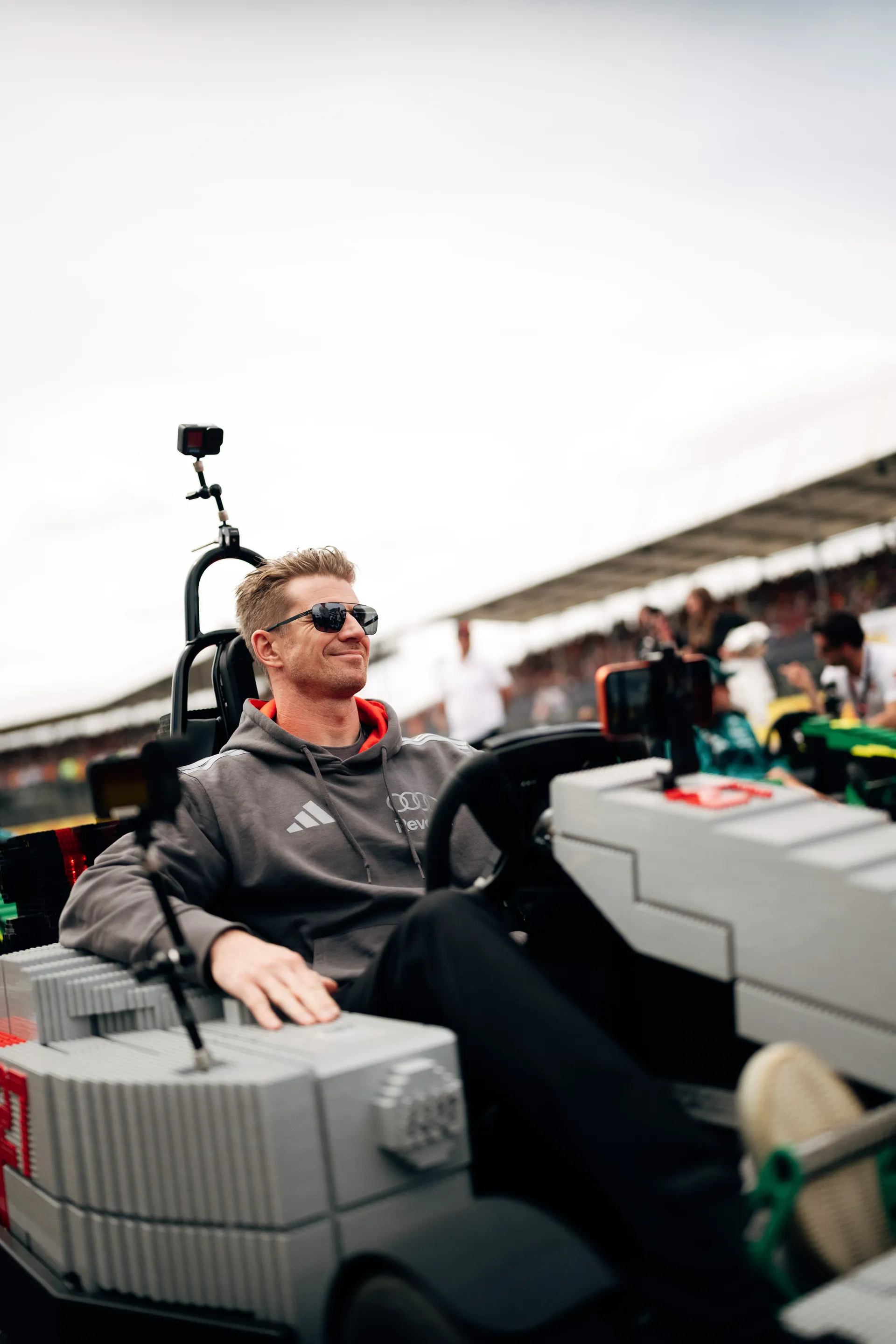 Nico Hulkenberg driving a LEGO® Audi R26 kart during the Drivers’ Parade, waving to the crowd.