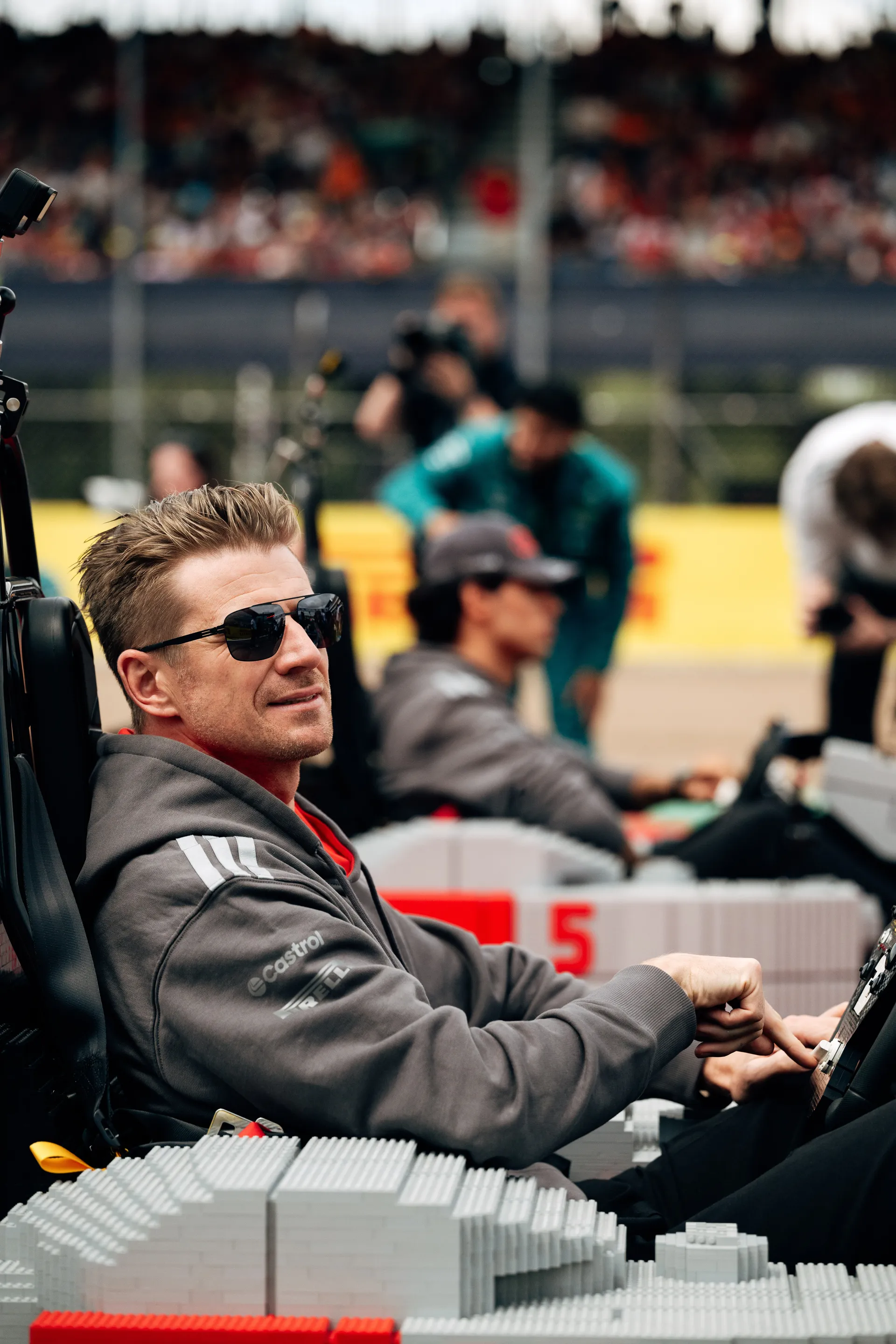 Nico Hulkenberg and Gabriel Bortoleto racing LEGO® karts on track during the Drivers’ Parade at Silverstone with grandstands in the background.