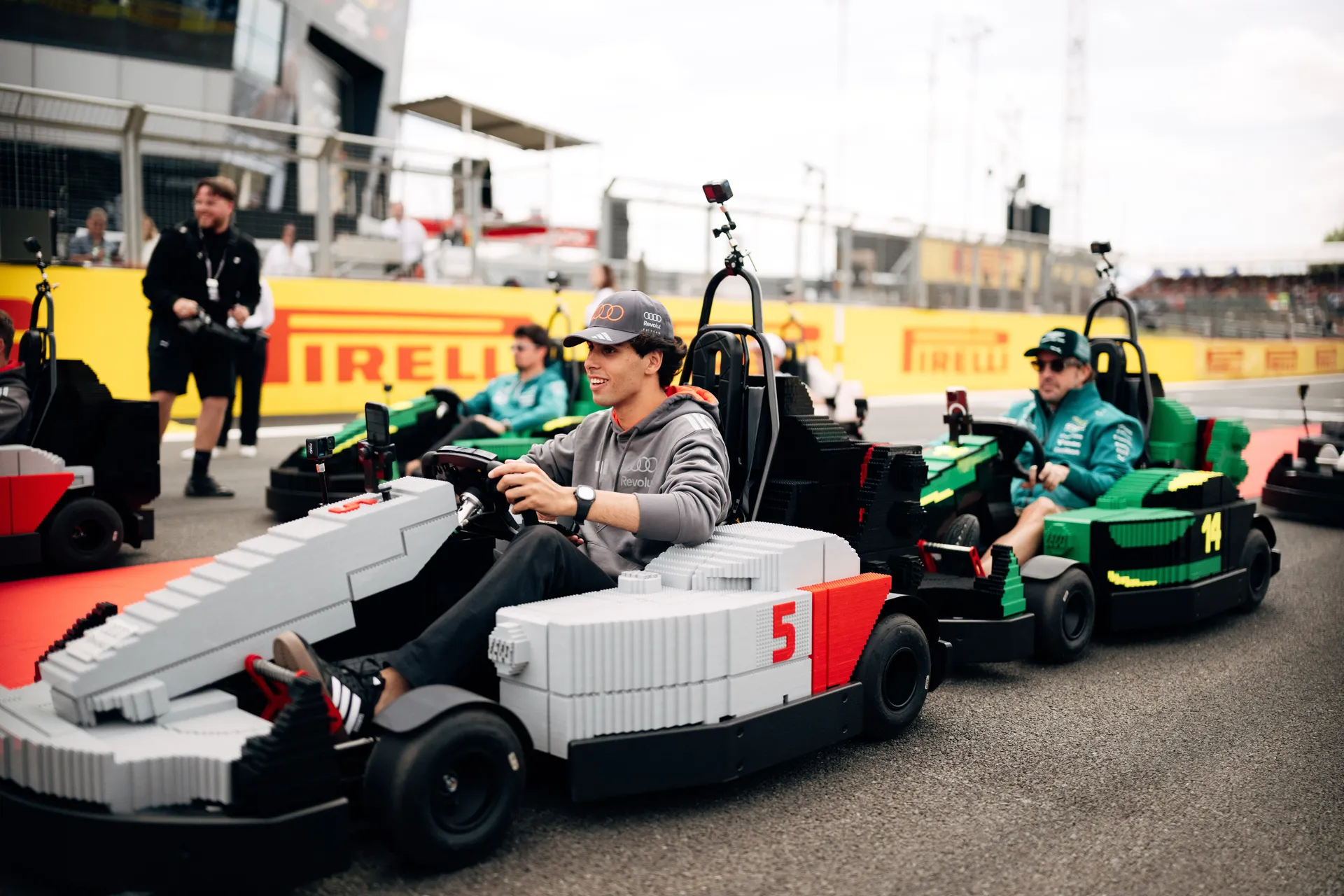 Gabriel Bortoleto driving a LEGO® Audi R26 kart during the Drivers’ Parade at Silverstone, followed by other drivers on track.