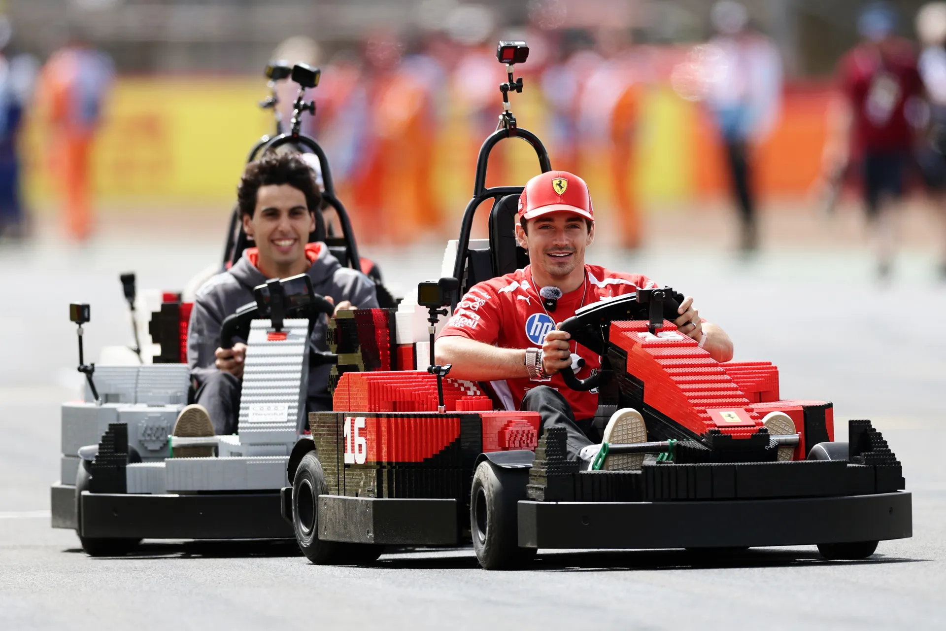 Charles Leclerc leading in a red kart with Gabriel Bortoleto following in an Audi R26 LEGO kart during the Silverstone drivers’ parade.