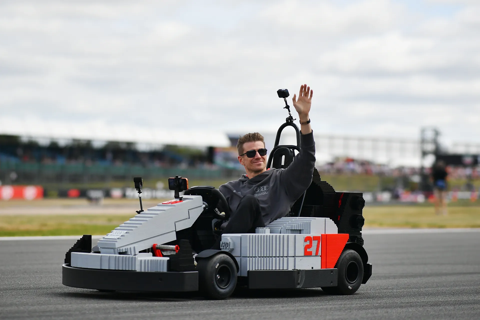 Nico Hulkenberg waving from an Audi R26 LEGO kart while driving along the Silverstone circuit during the drivers’ parade.