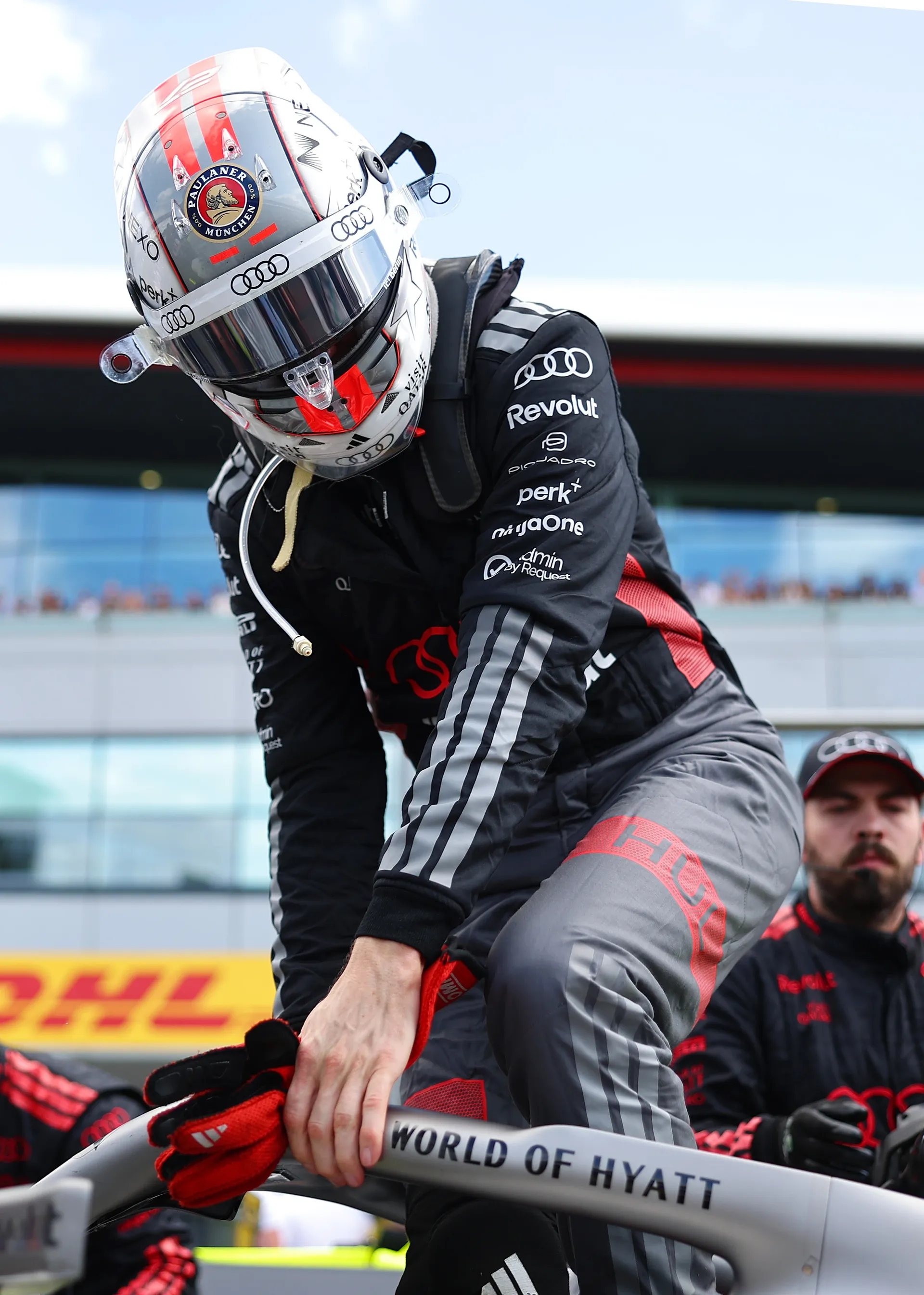 Nico Hulkenberg wearing helmet and race suit while climbing out of the Audi R26 on the grid.