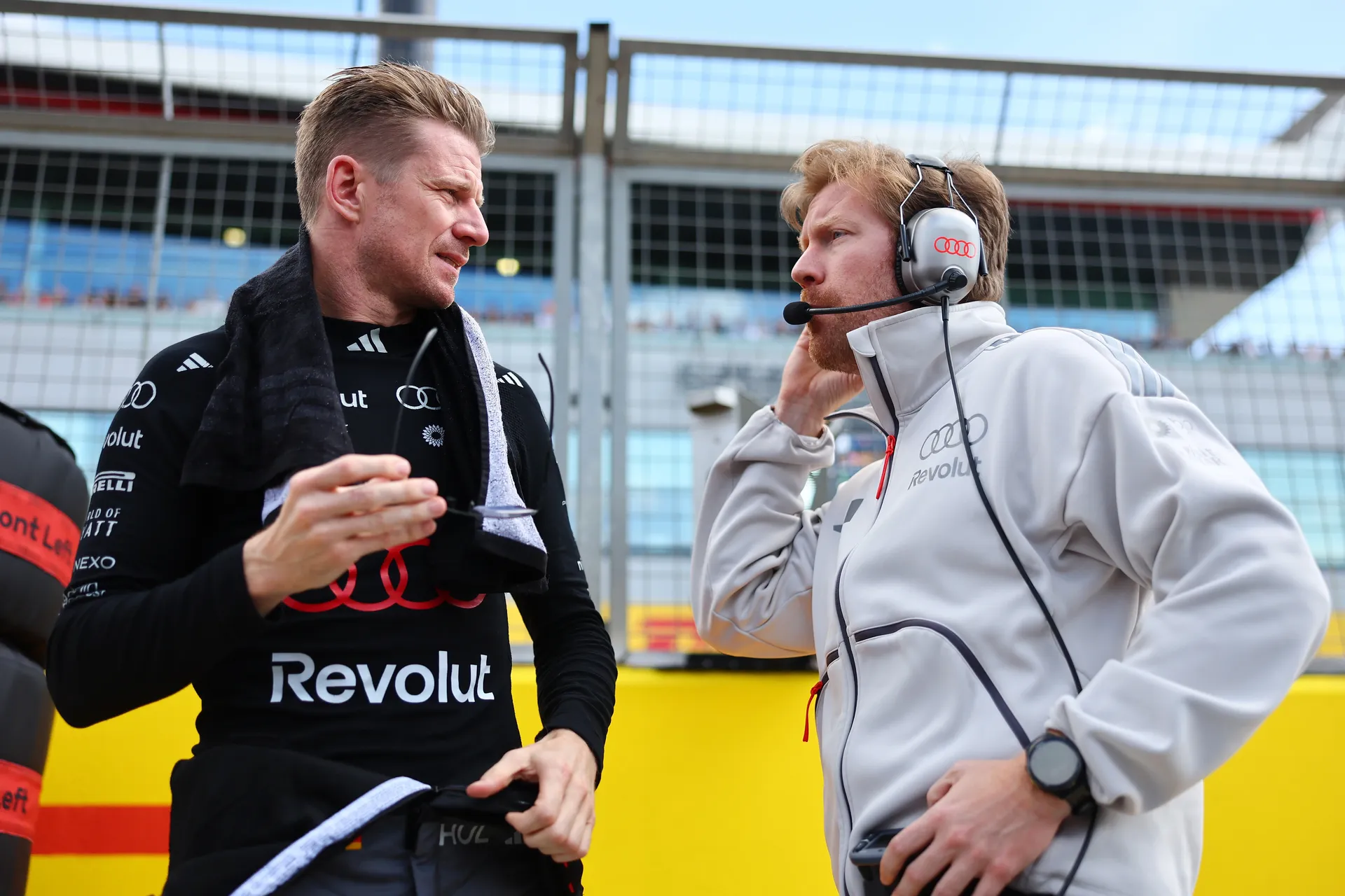 Nico Hulkenberg speaking with a race engineer on the grid, holding a balaclava while discussing setup.