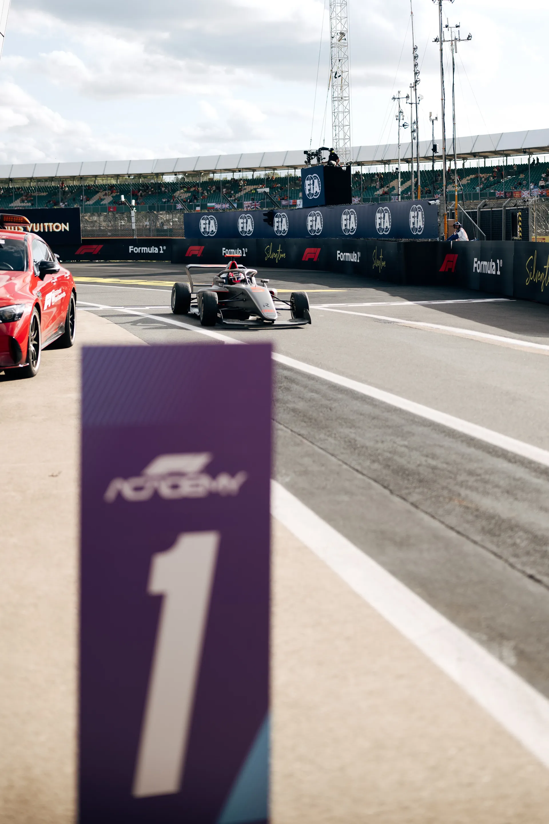 Emma Felbermayr driving in first position with her F1 Academy car on the Silverstone grid with the number 1 position board in the foreground.
