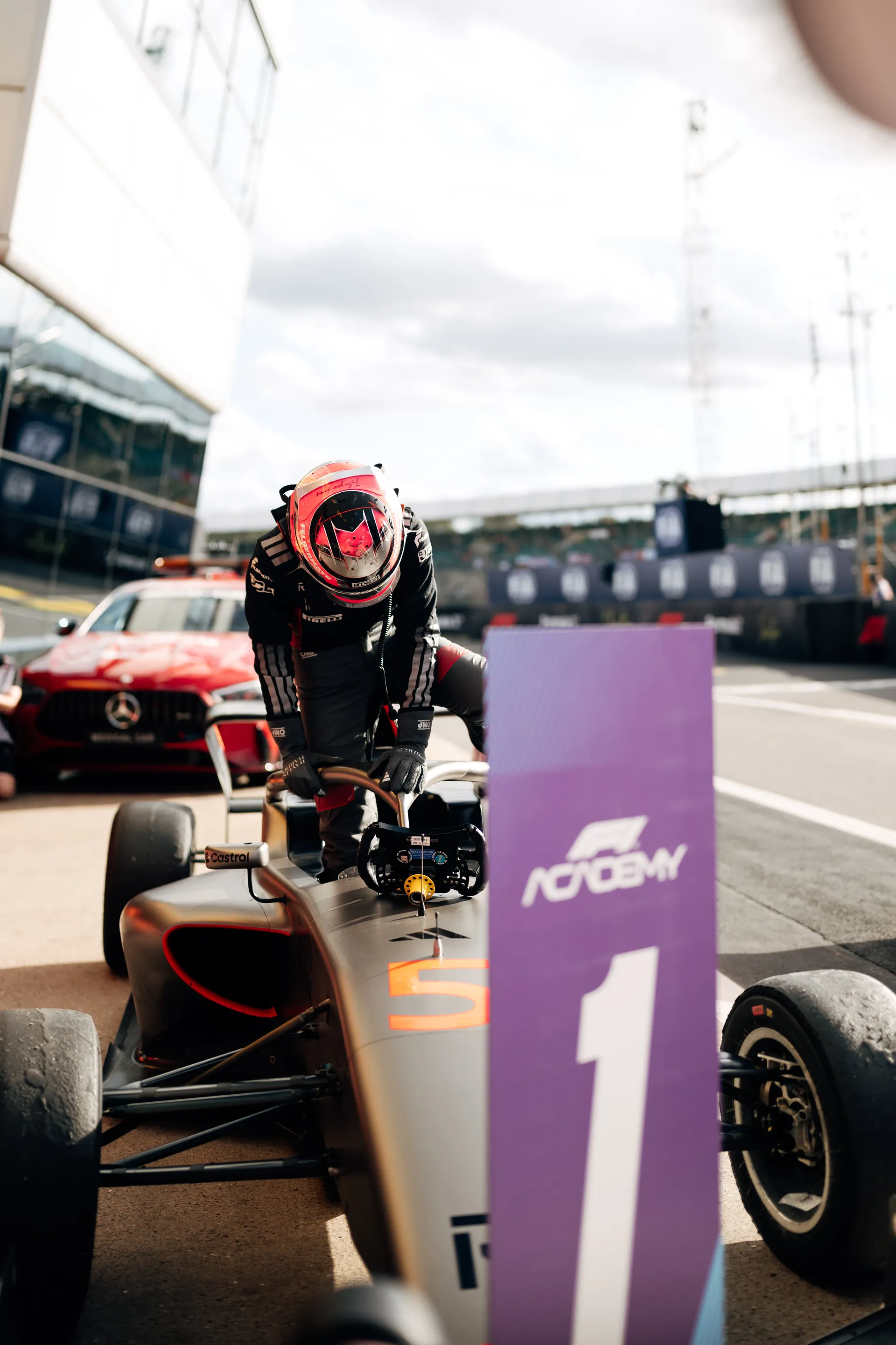 Emma Felbermayr stepping out of her F1 Academy car on the Silverstone grid with the number 1 position board in the foreground.
